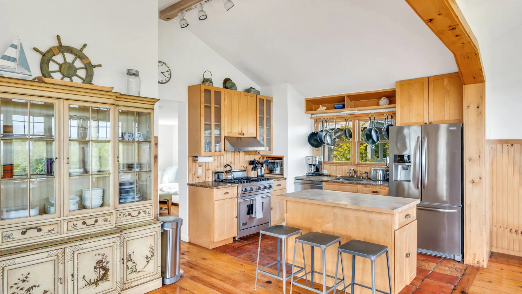 Una cocina amplia con gabinetes de madera, una isla central y electrodomésticos de acero inoxidable.