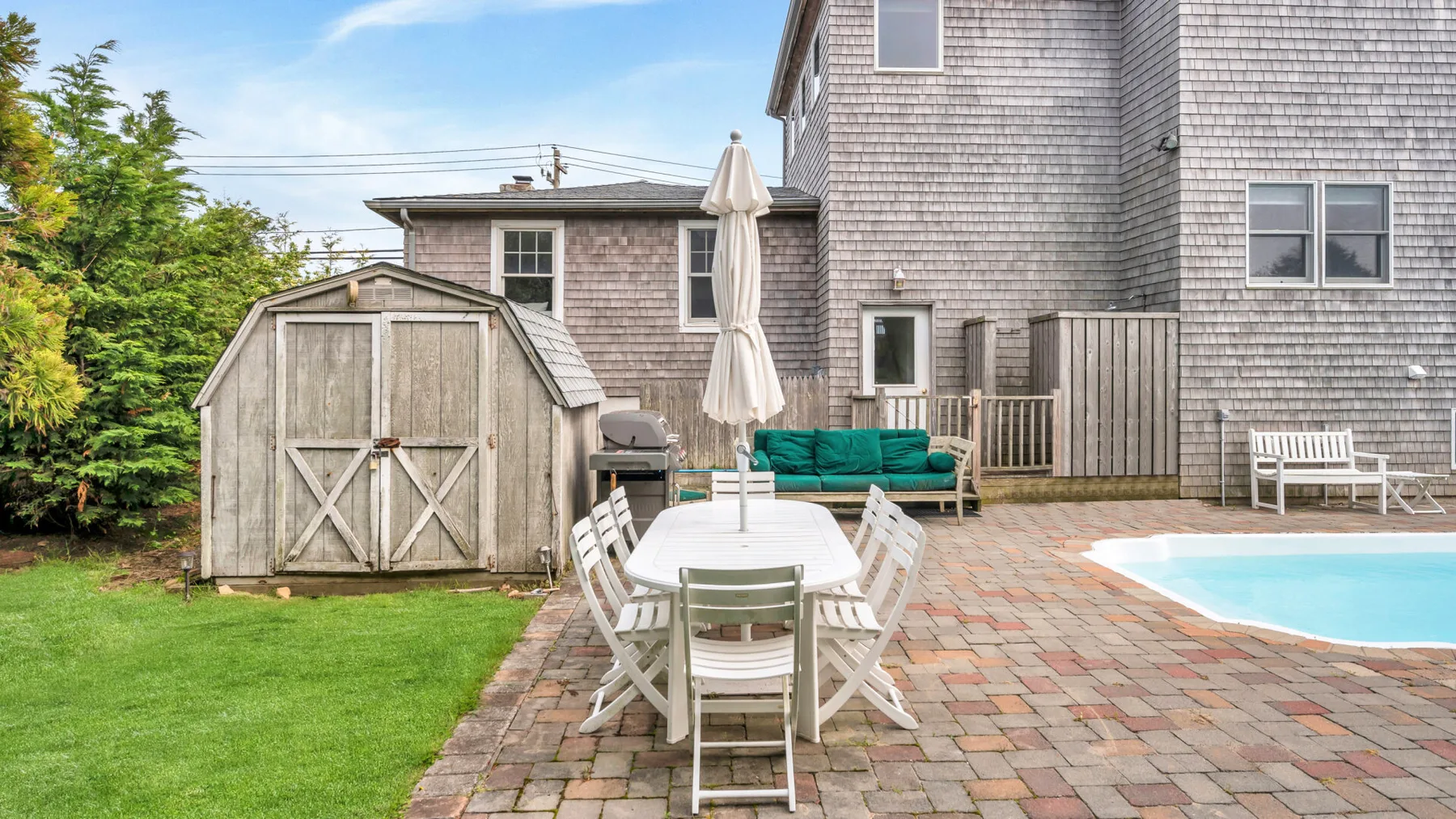 Un patio exterior con comedor junto a una casa y una piscina.