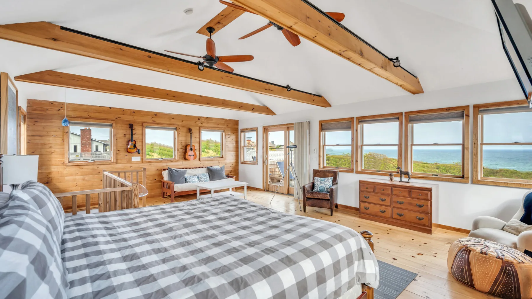 Un dormitorio con una cama grande, vigas de madera y ventanas con vistas al paisaje.