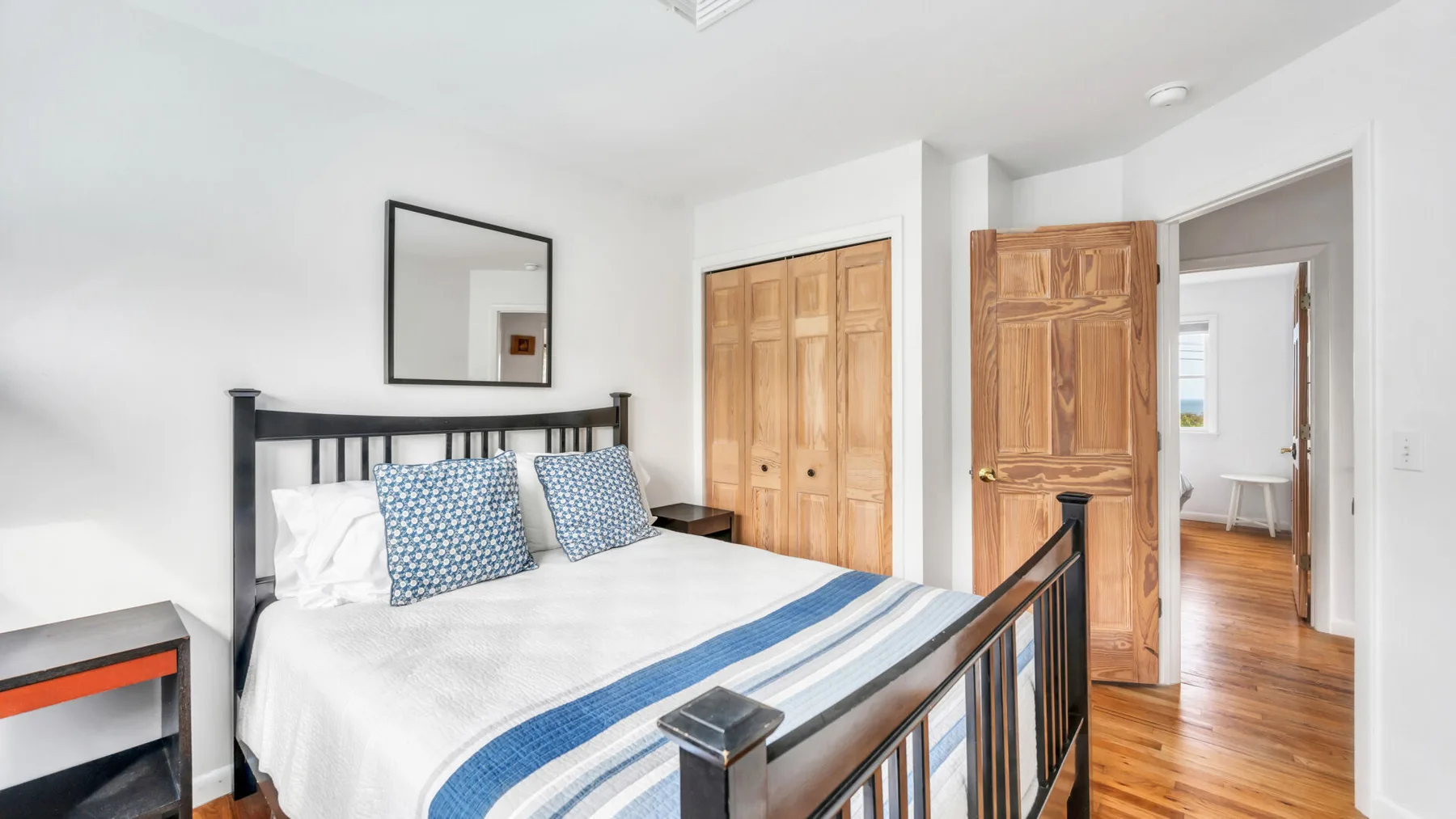 Un dormitorio con una cama, almohadas estampadas y puertas de madera.
