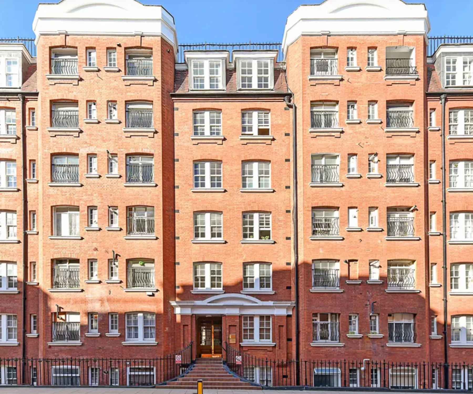 A red-brick apartment building with rows of windows and a central entrance.