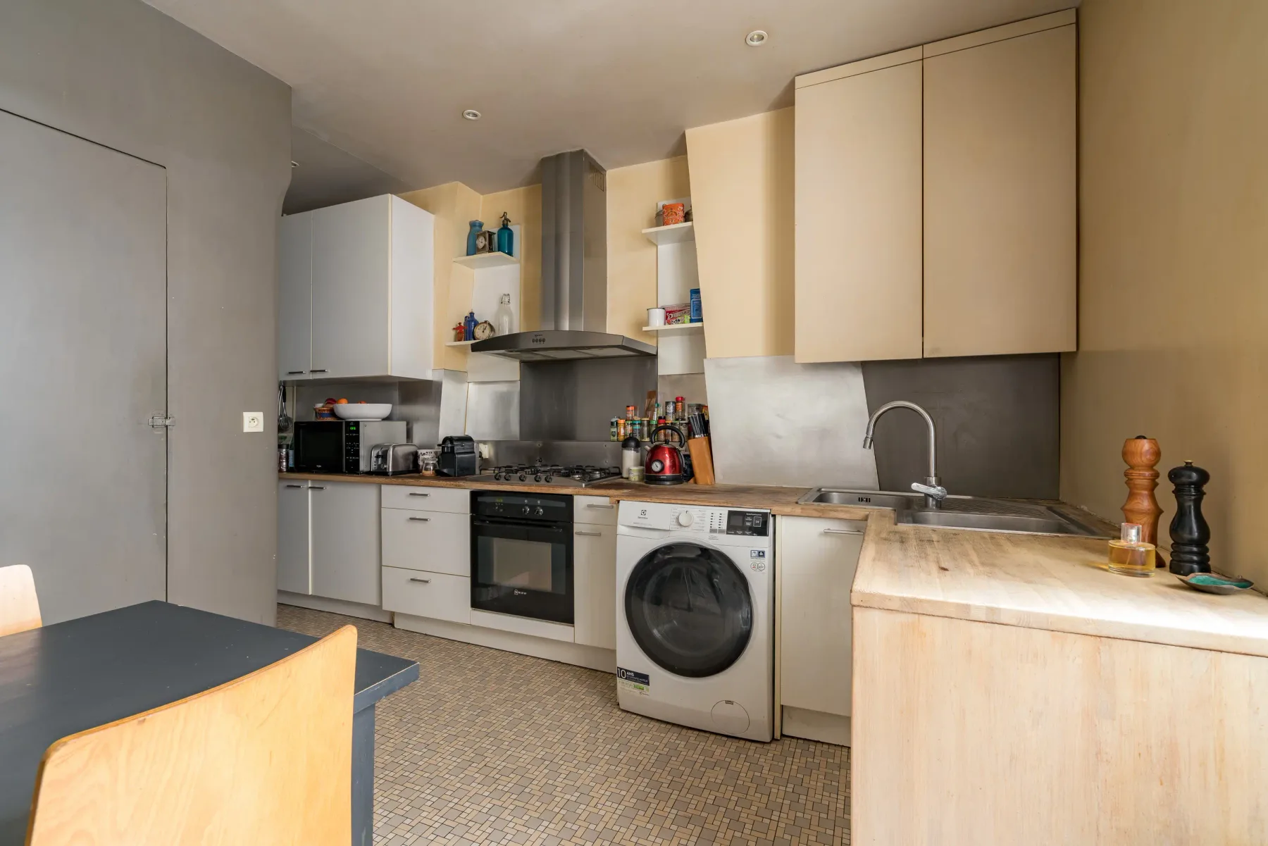 A compact kitchen with pale cabinets, a countertop, and a washing machine.
