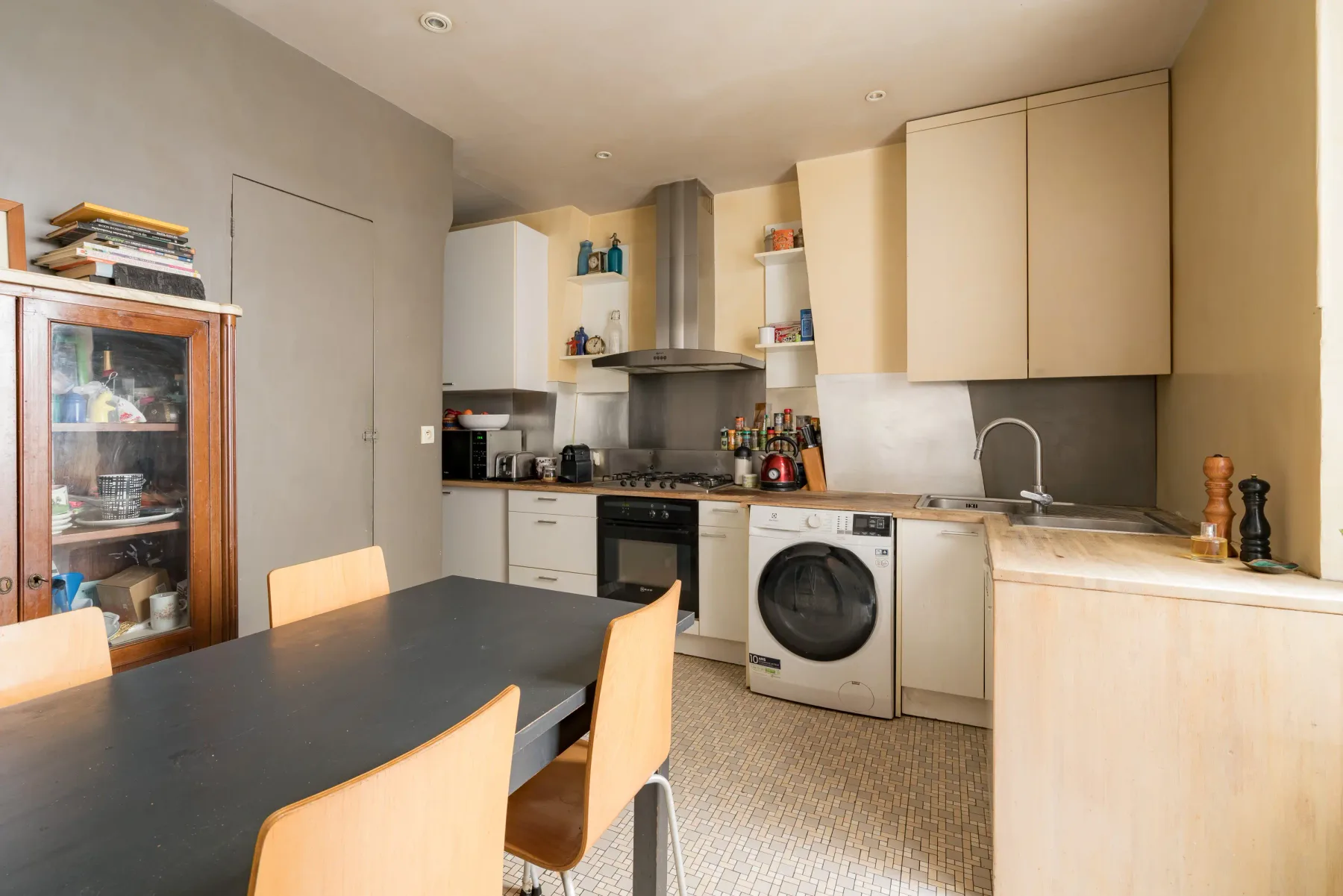 A kitchen with a dark dining table and light wood cabinets.