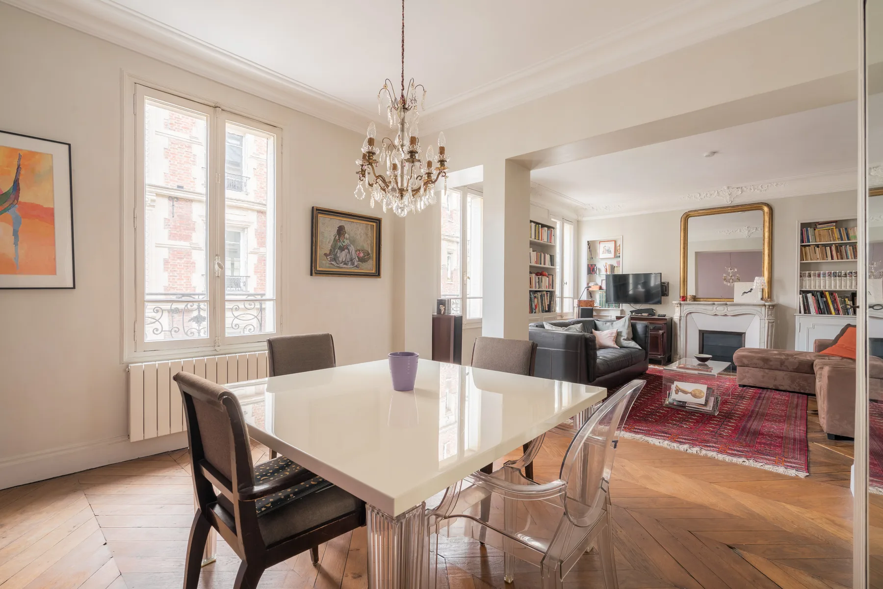 A dining area with a table and chandelier opens into a living room.
