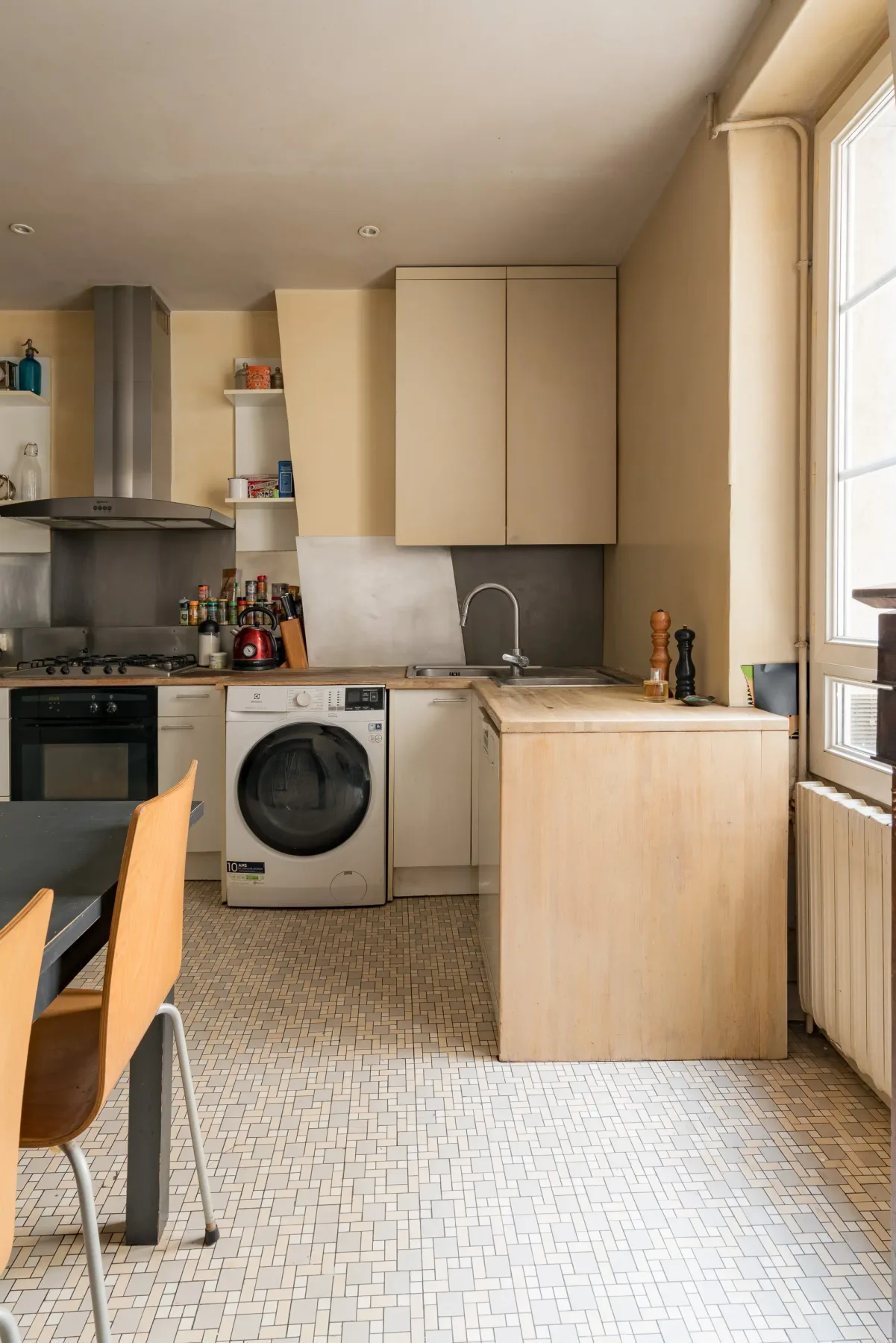 A compact kitchen with light cabinets, a sink, and a washing machine.