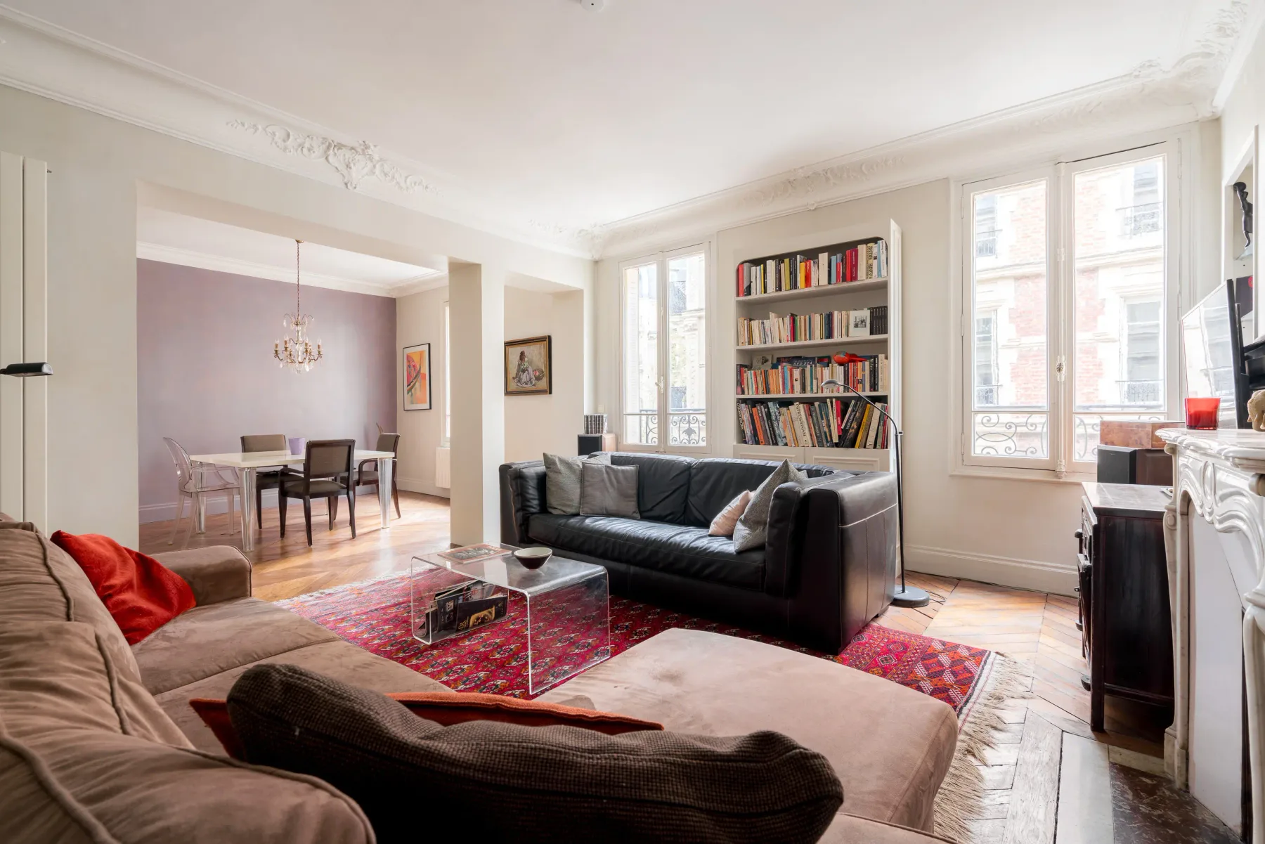 A bright living room with seating, a coffee table, and a bookcase.