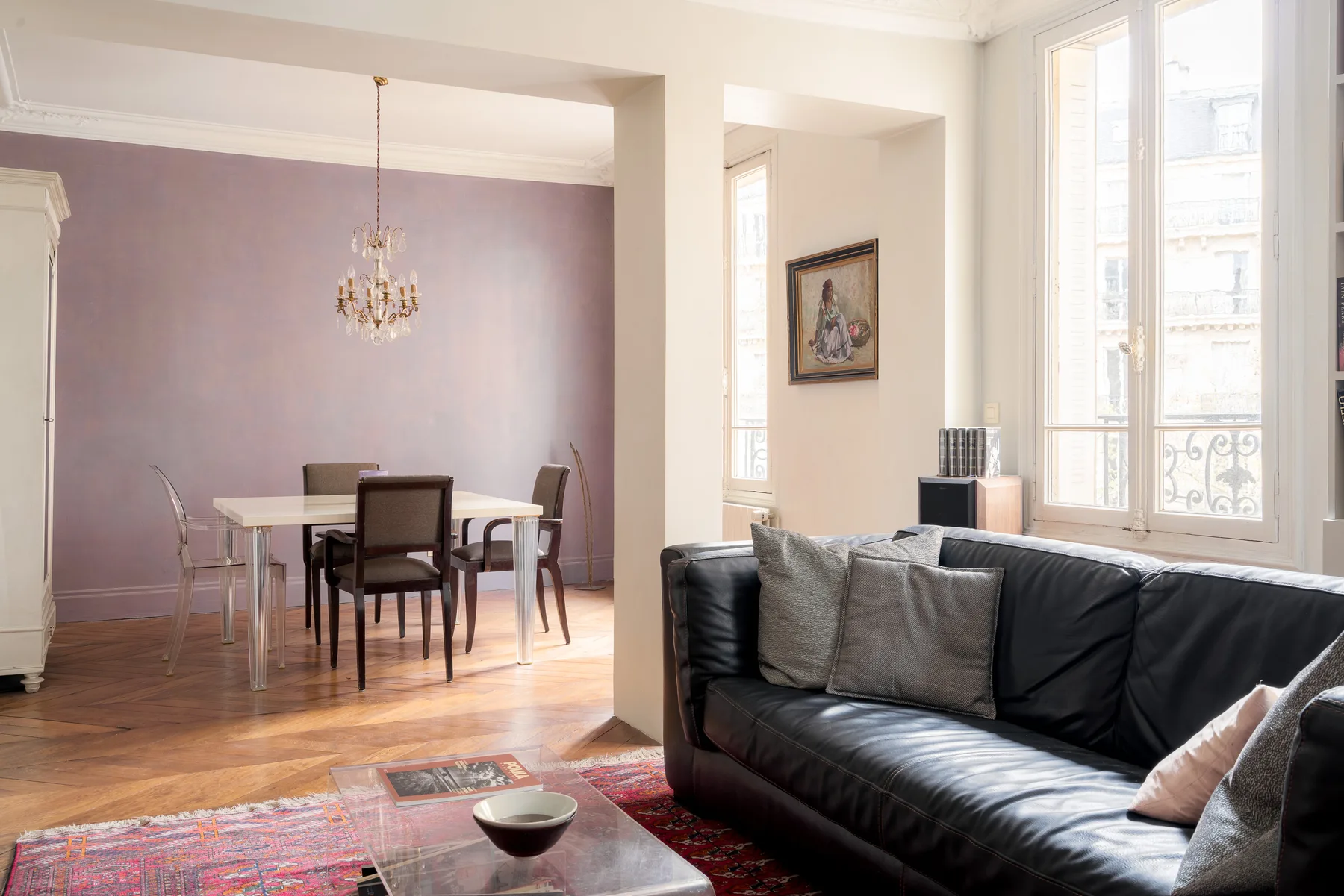 A bright living and dining area with seating beside tall windows.