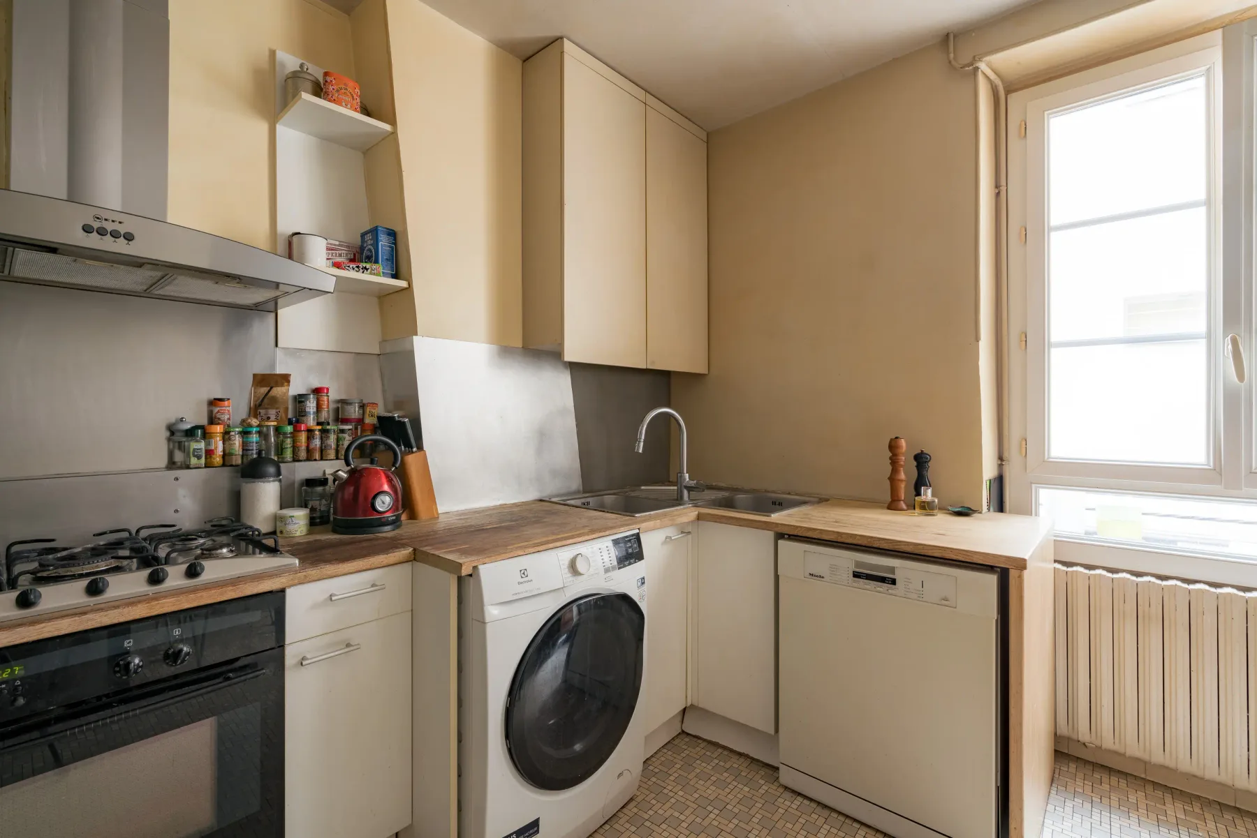 A compact kitchen with light cabinetry, a countertop, and a window.