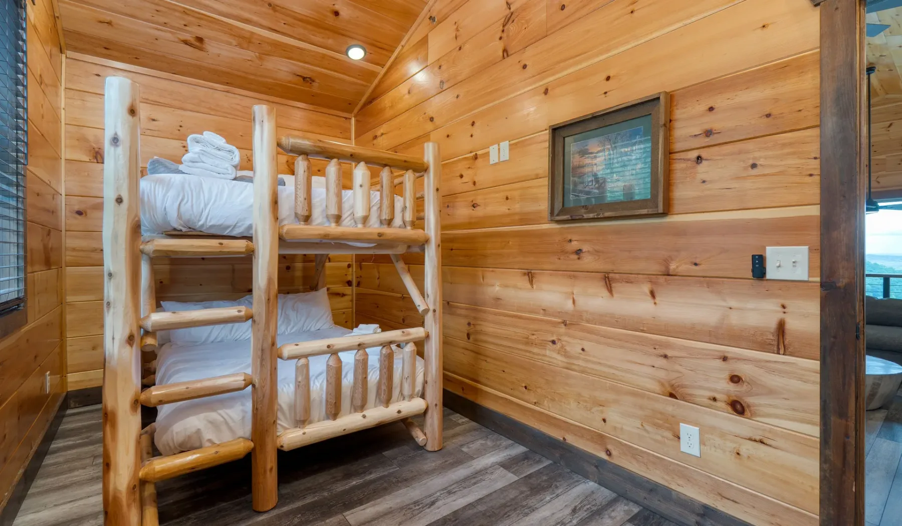 Un dormitorio revestido de madera con una litera de madera y un cuadro enmarcado.