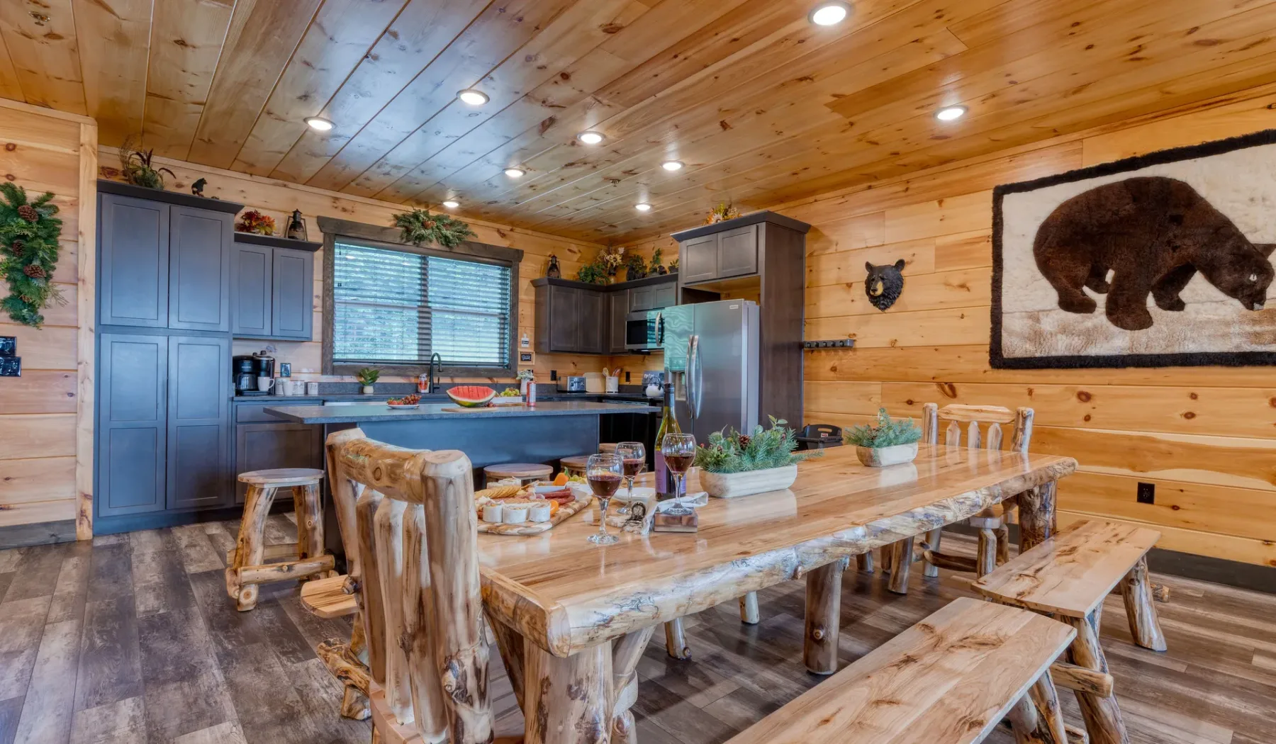 Cocina y comedor revestidos de madera, con una gran mesa rústica.