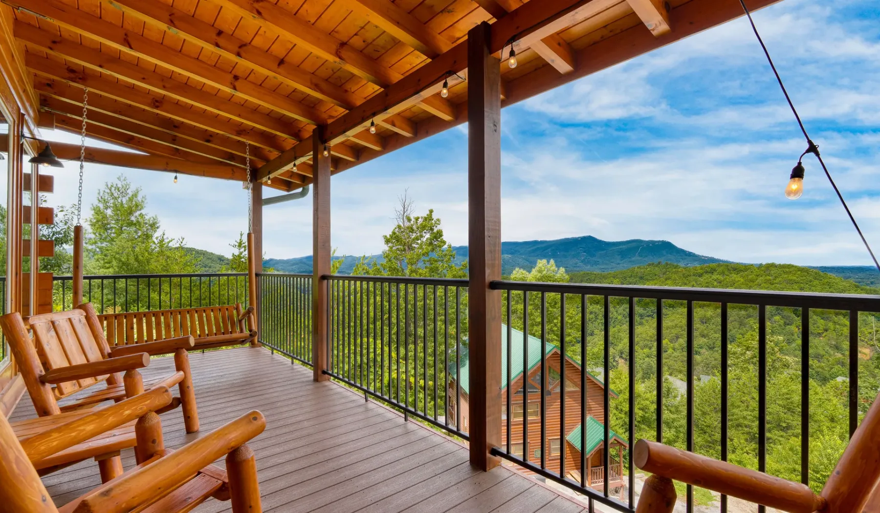 Una terraza exterior cubierta con asientos de madera da a un paisaje montañoso verde.