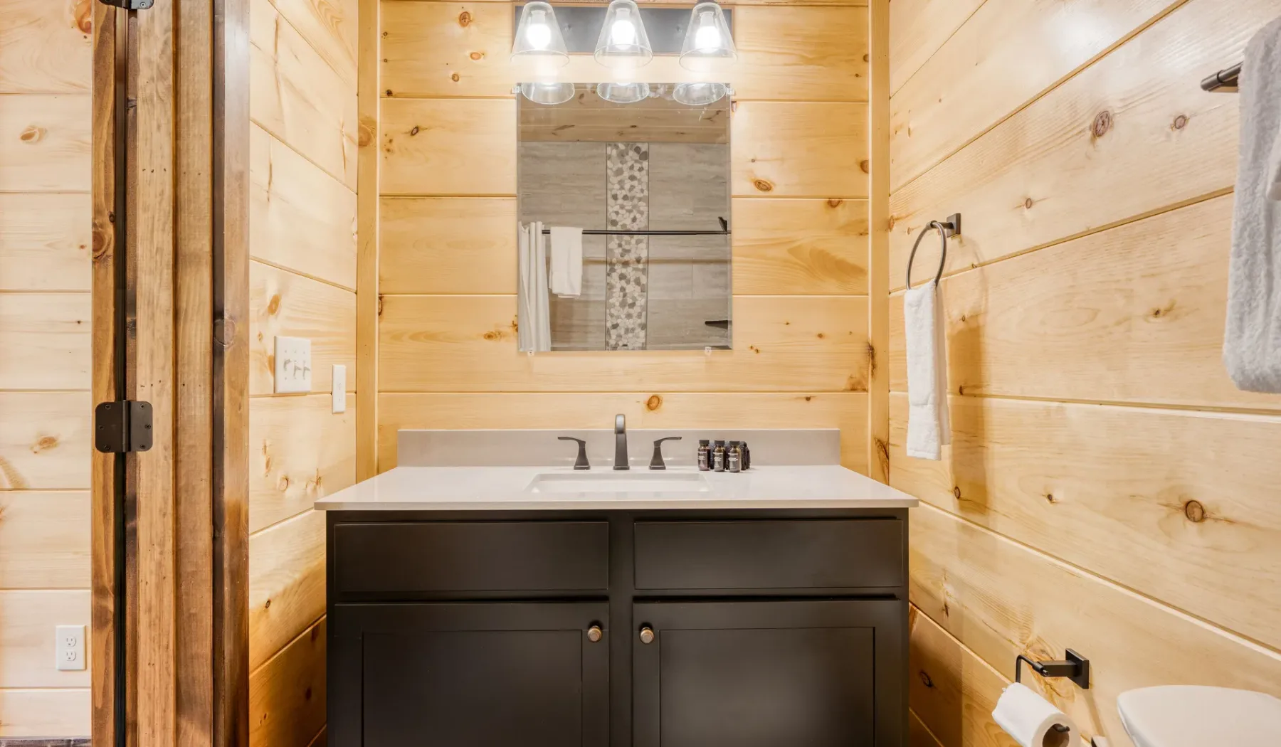 Un mueble de baño con lavabo y espejo está junto a paredes revestidas de madera.