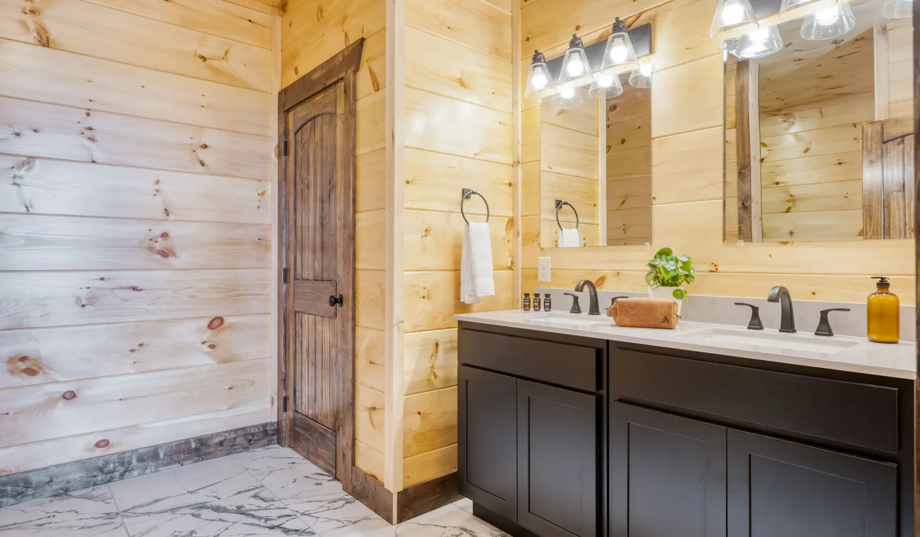 Baño revestido de madera con tocador doble y espejos.