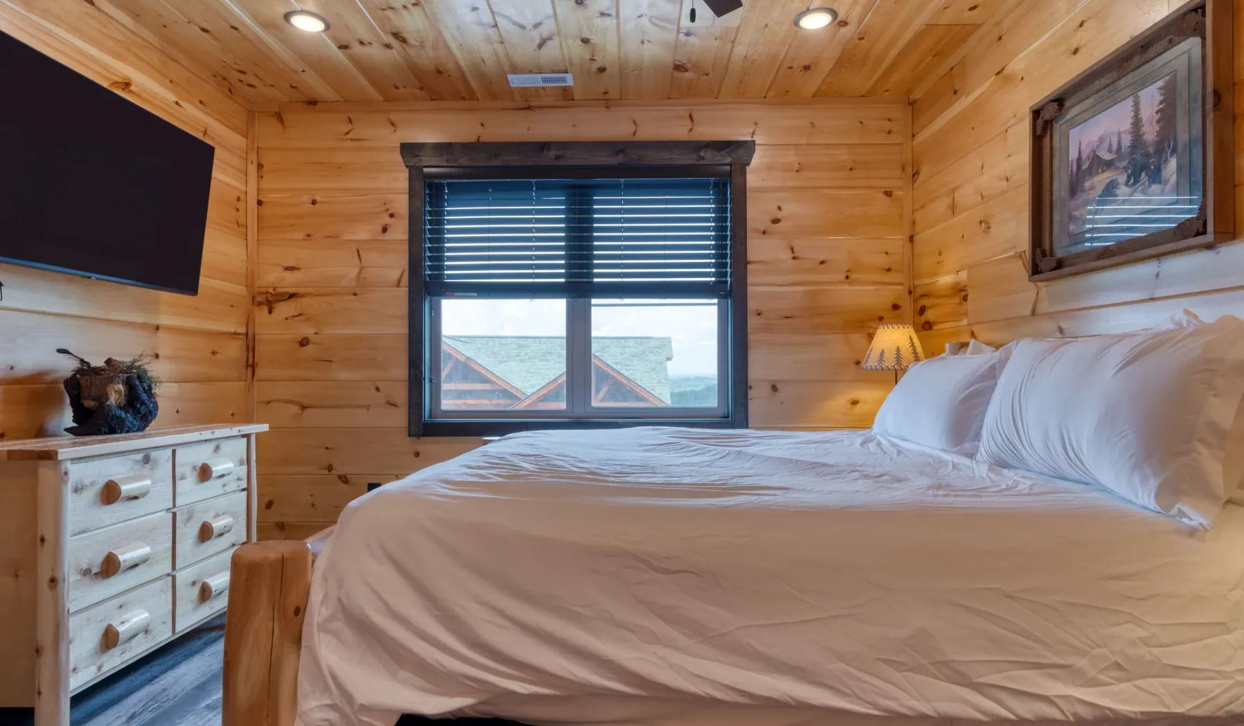 Un dormitorio con una cama grande, paredes revestidas de madera y una ventana con persianas.