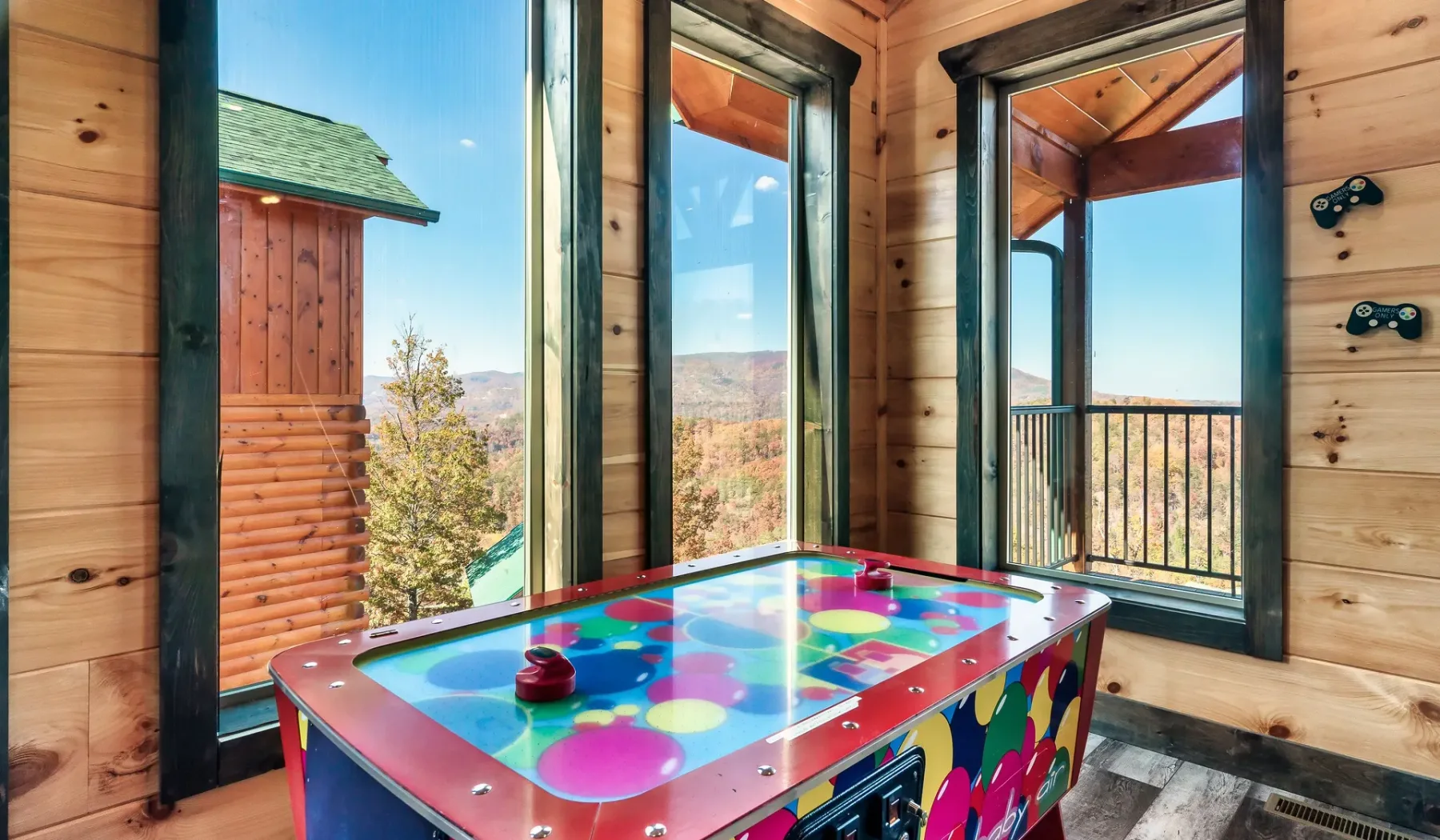 Una mesa de hockey de aire colorida está en una habitación revestida de madera con grandes ventanas.