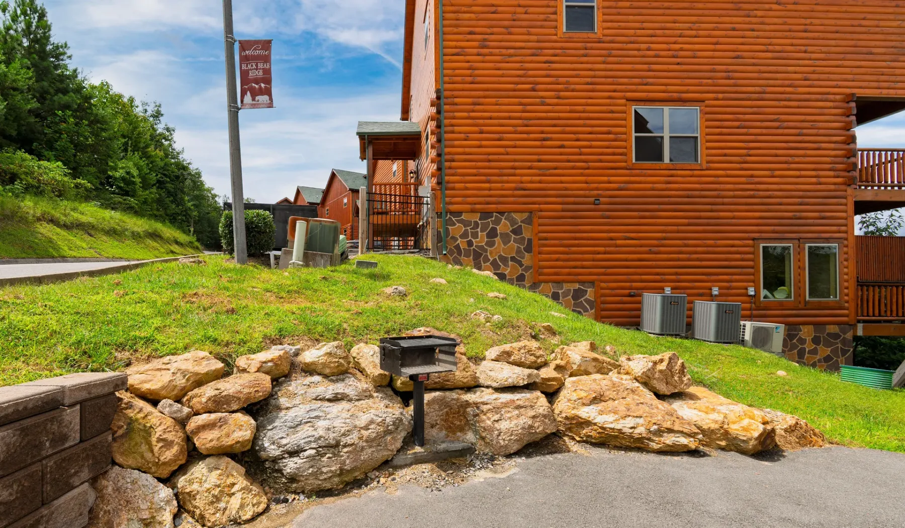 Un edificio revestido de troncos se alza junto a una ladera cubierta de hierba y un muro bajo de piedra.