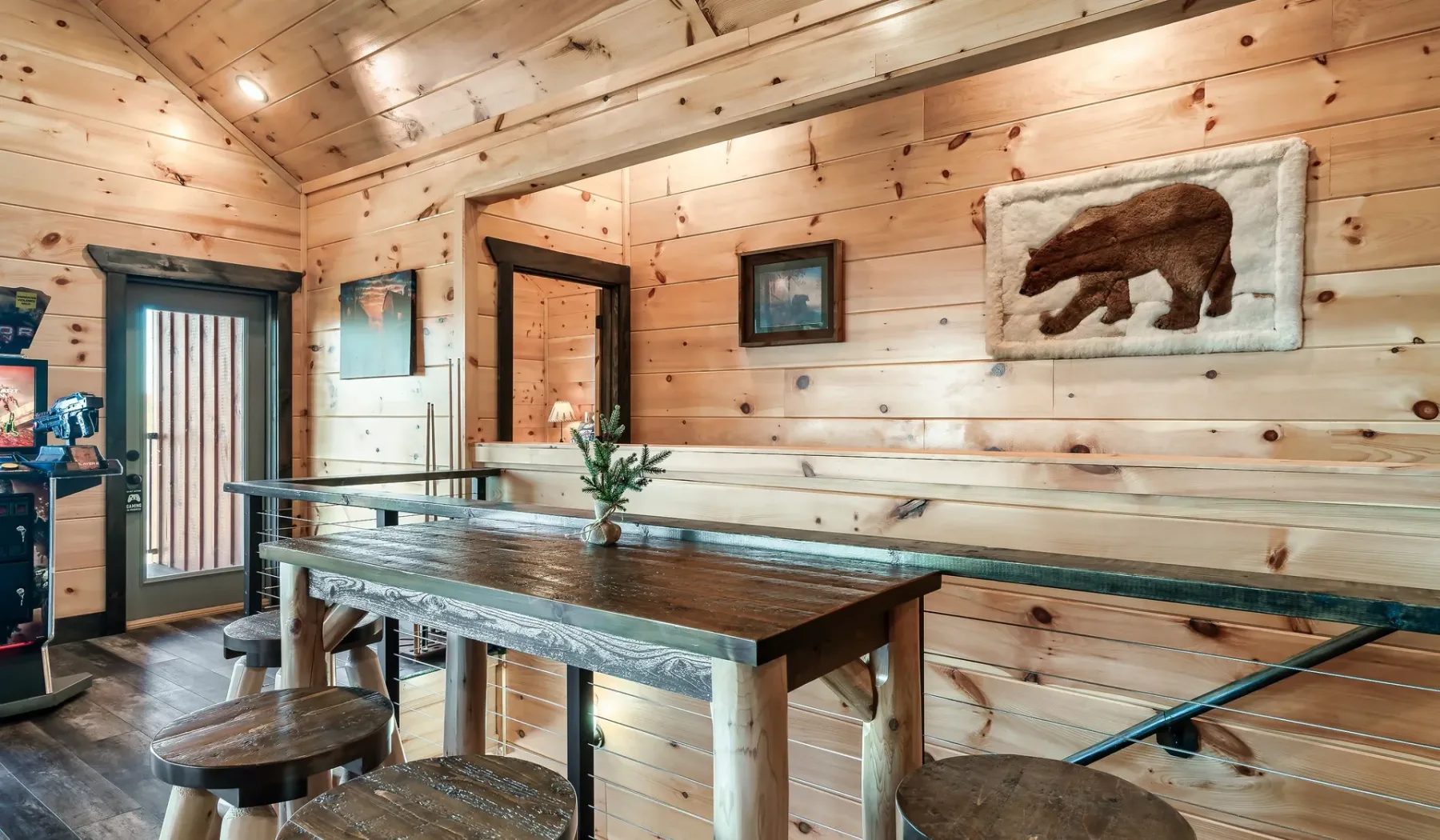 Comedor revestido de madera con una mesa larga y taburetes.