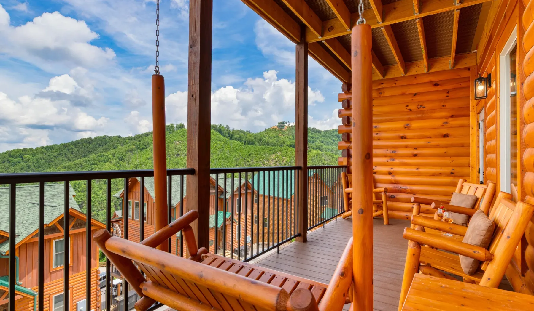 Una terraza de madera con asientos ofrece vistas a un lago y colinas verdes.