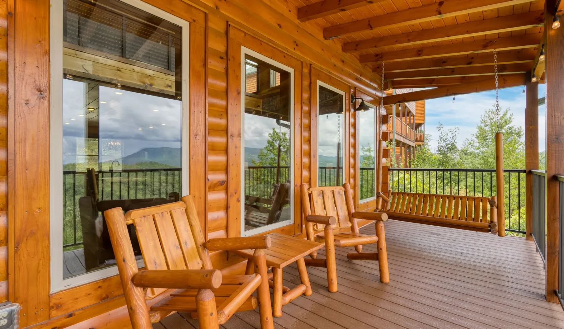 Una terraza de madera cubierta con asientos da a un paisaje montañoso verde.