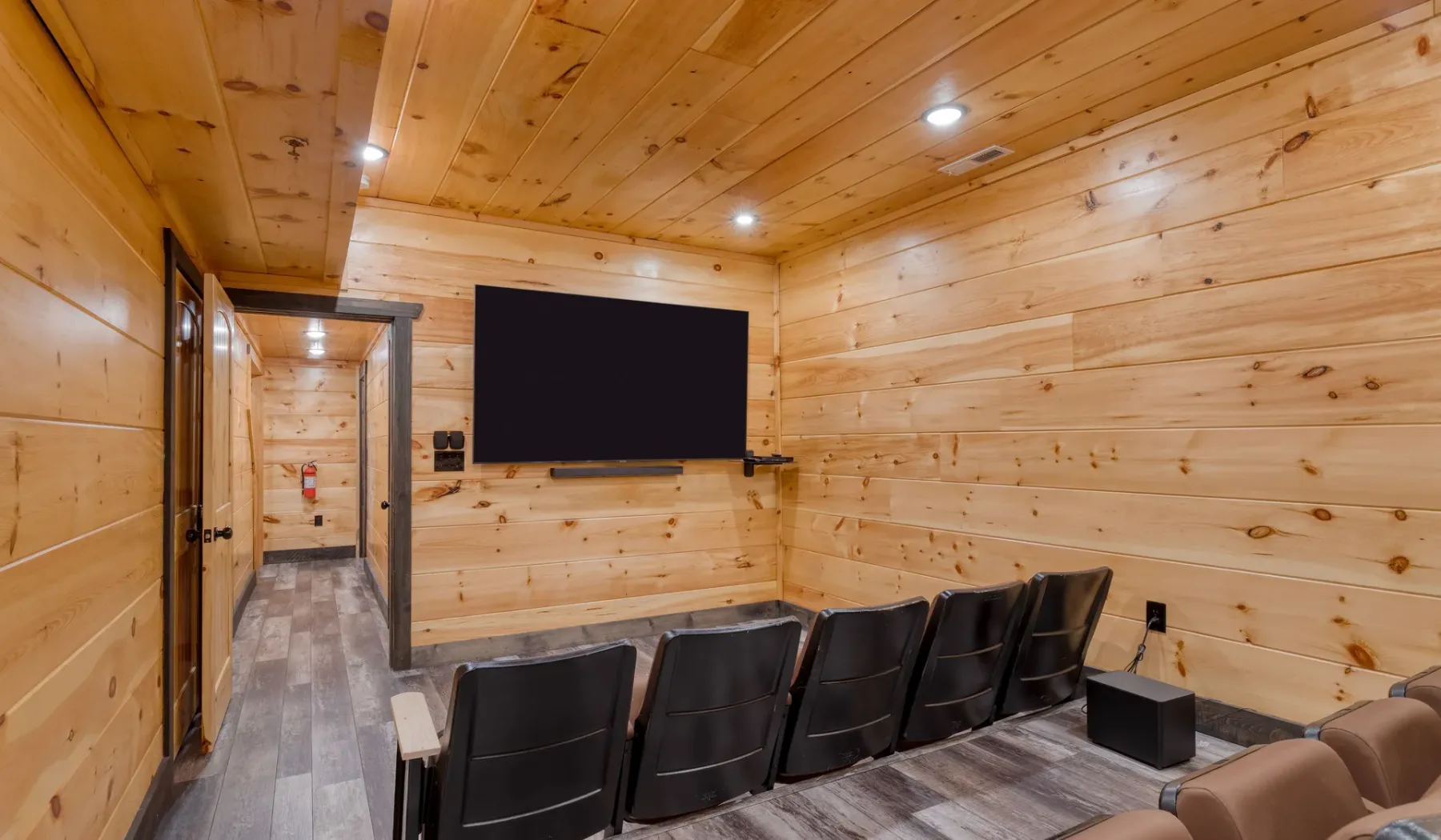 Sala de medios revestida de madera con una pantalla en la pared y asientos en filas.