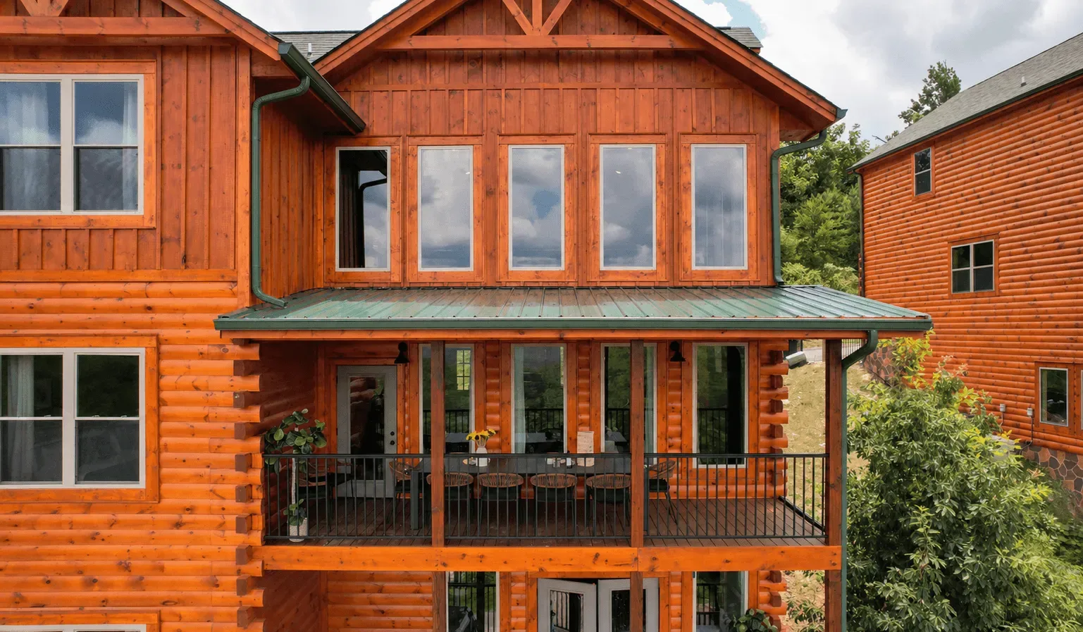 Una casa grande de madera con un balcón cubierto y filas de ventanas.