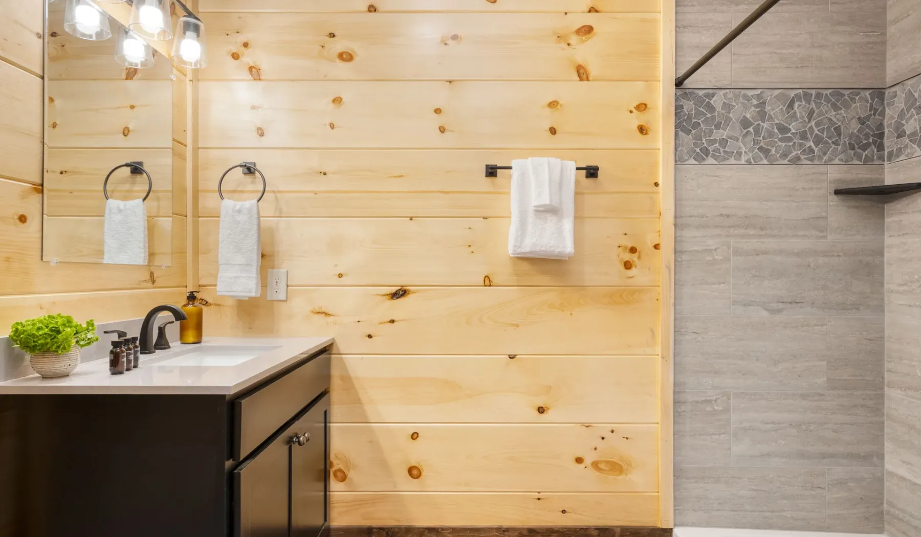 Un tocador de baño con espejo y una zona de ducha contigua con azulejos.