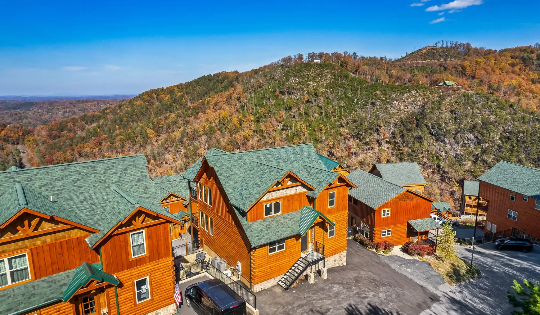 Cabañas se encuentran al pie de una ladera arbolada bajo un cielo azul despejado.