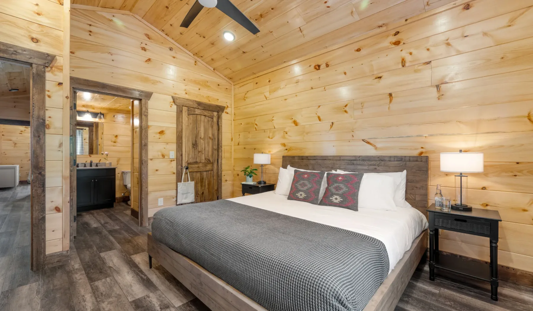 Un dormitorio revestido de madera con una cama grande y mesitas de noche.