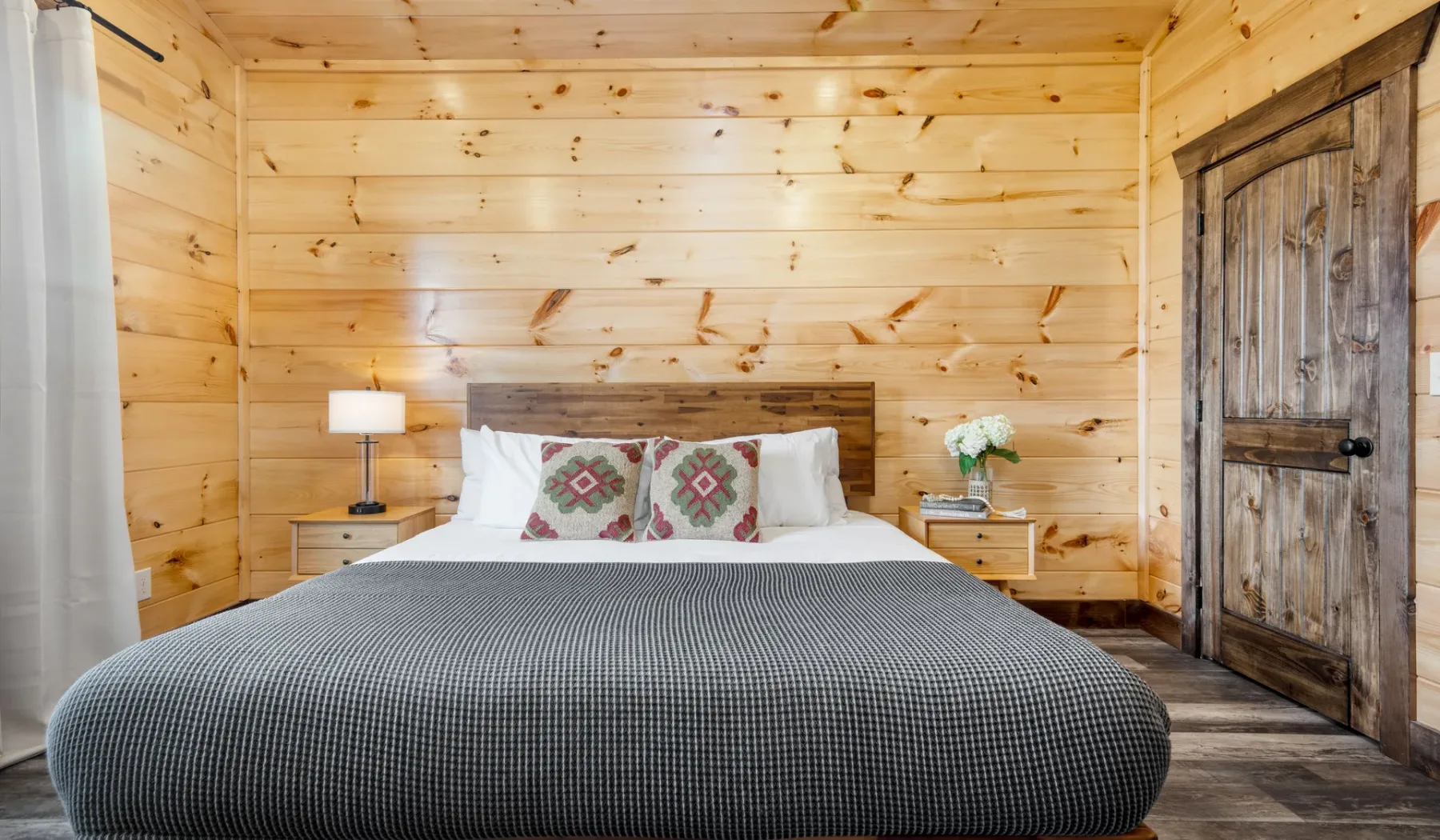 Un dormitorio con una cama grande, mesitas de noche y paredes revestidas de madera.