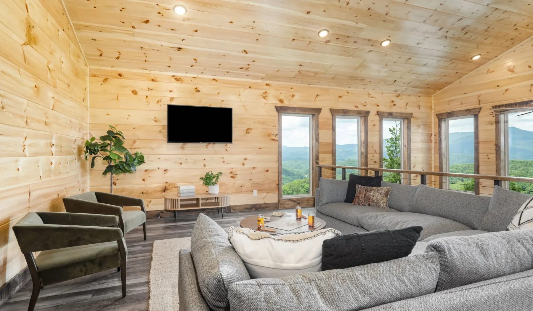 Sala de estar revestida de madera, con asientos seccionales y grandes ventanas.