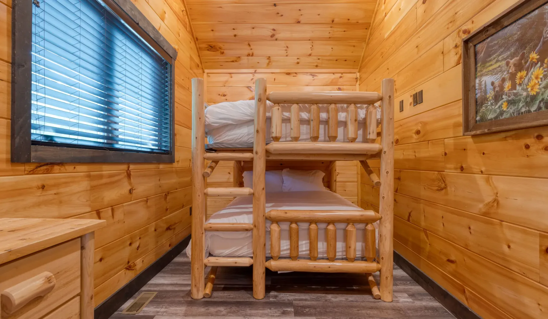 Un dormitorio con literas y paneles de madera, una ventana y un cuadro.