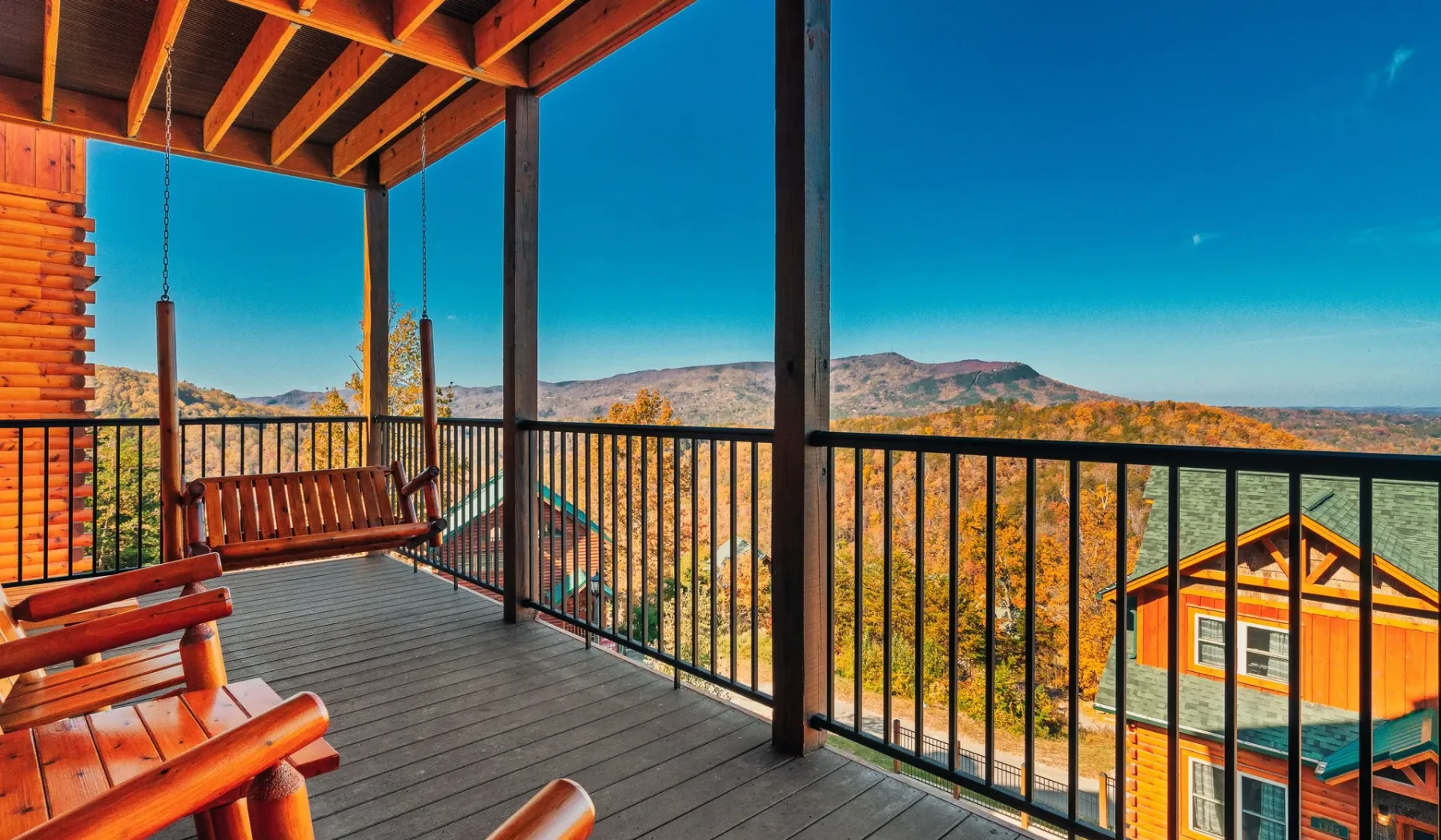 Una terraza de madera cubierta da a un paisaje montañoso boscoso.