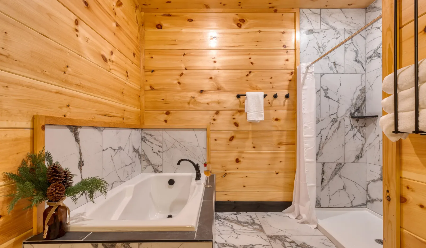 Un baño con bañera, ducha y paredes revestidas de madera.