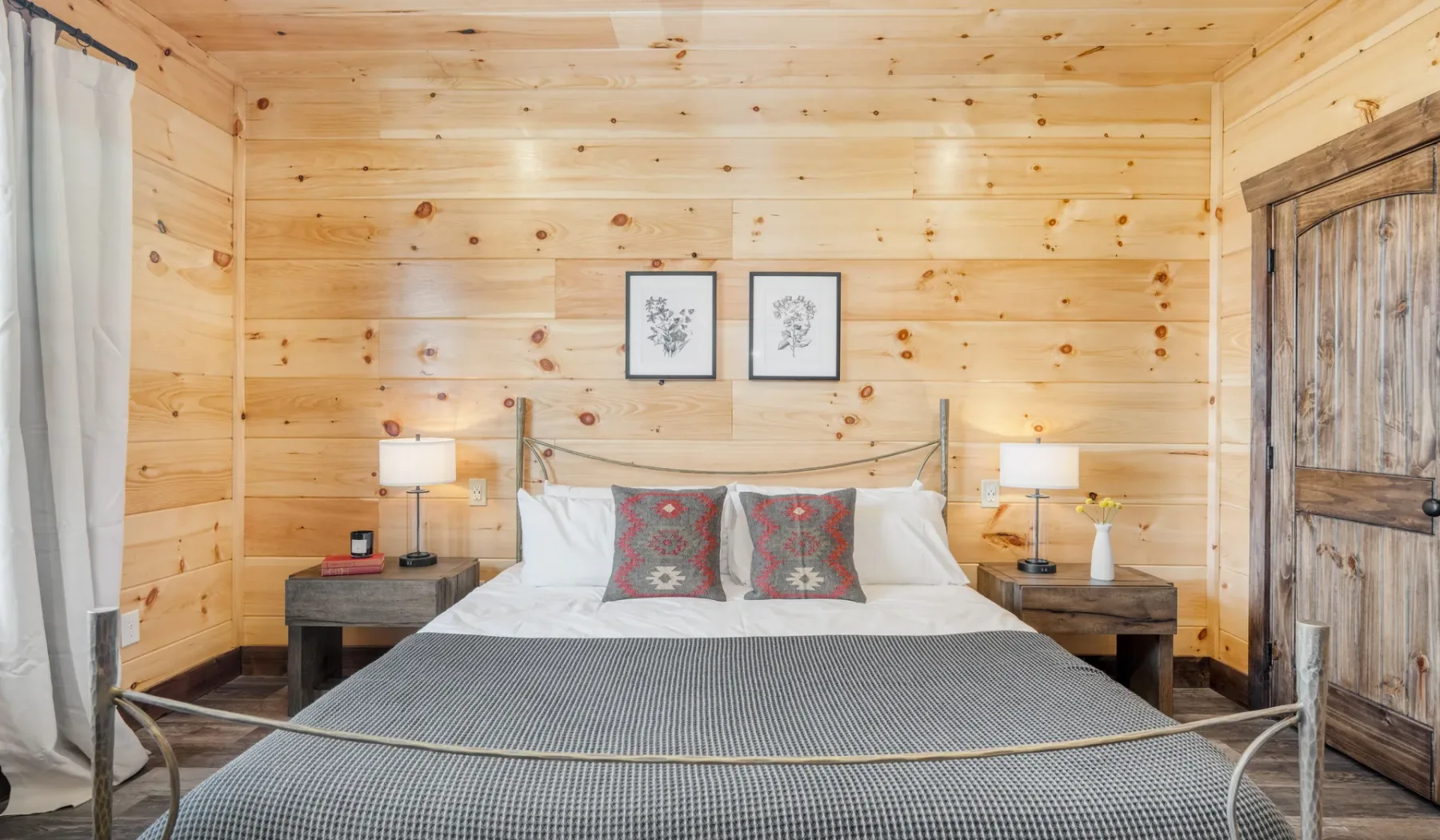 Un dormitorio con una cama grande, mesitas de noche y paredes revestidas de madera.