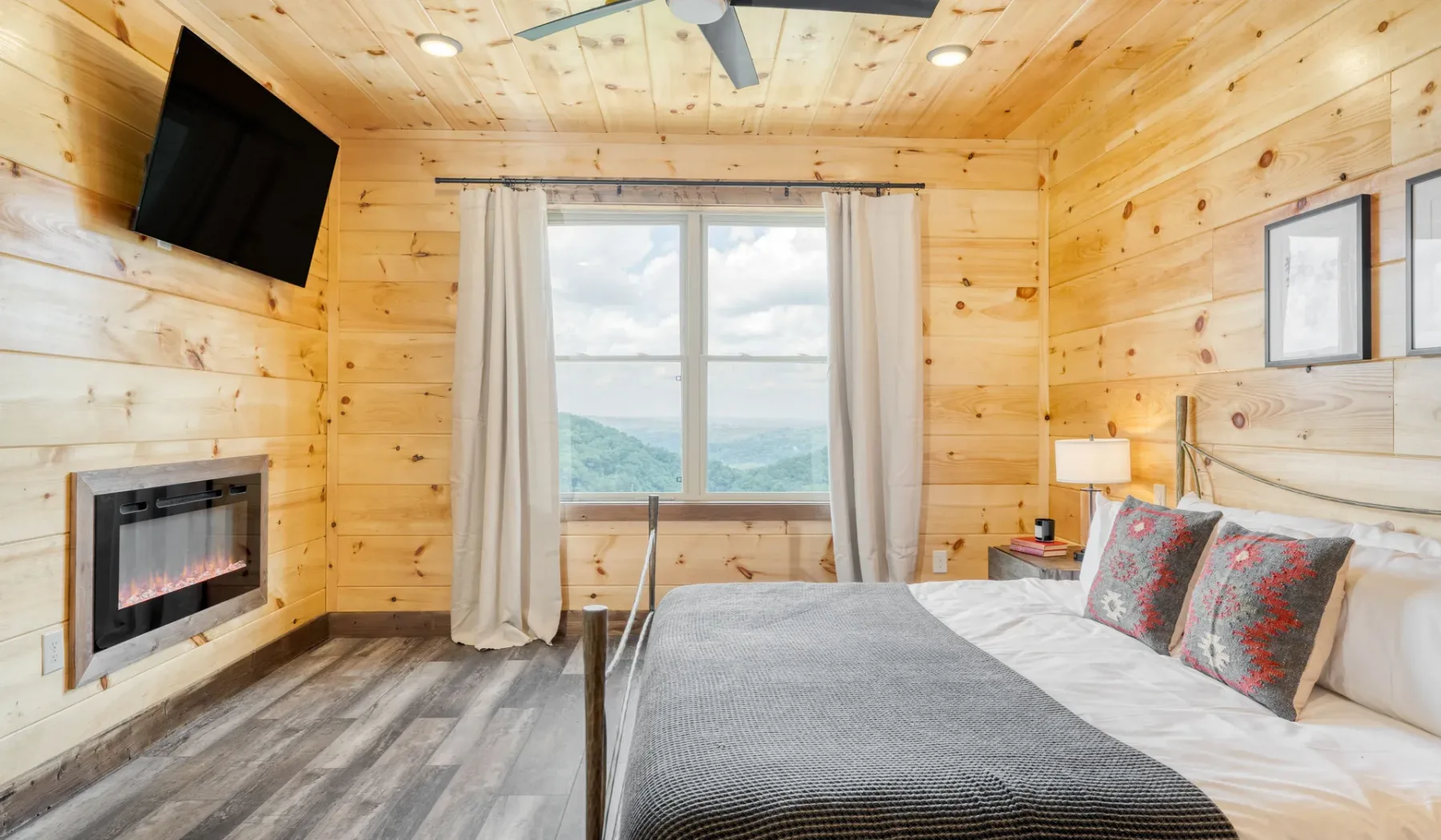 Un dormitorio revestido de madera con una cama junto a una ventana grande.