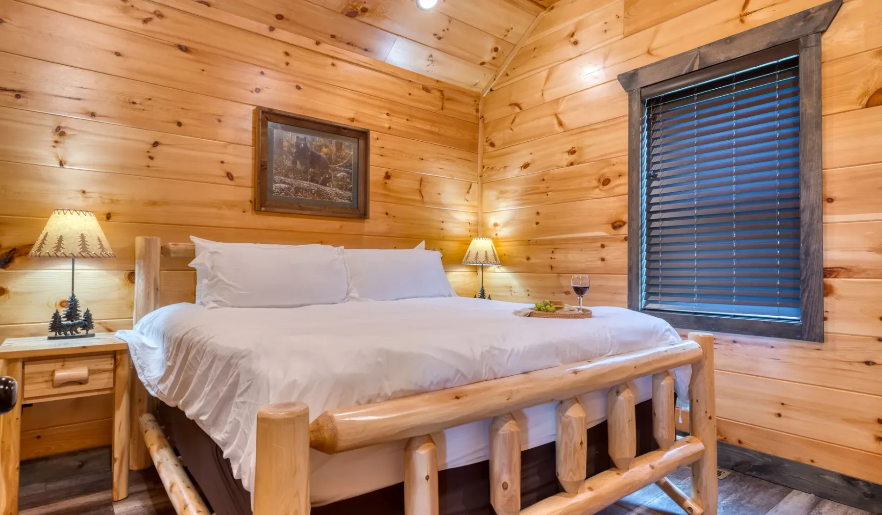 Dormitorio con una cama, paredes de madera y una ventana con persianas.