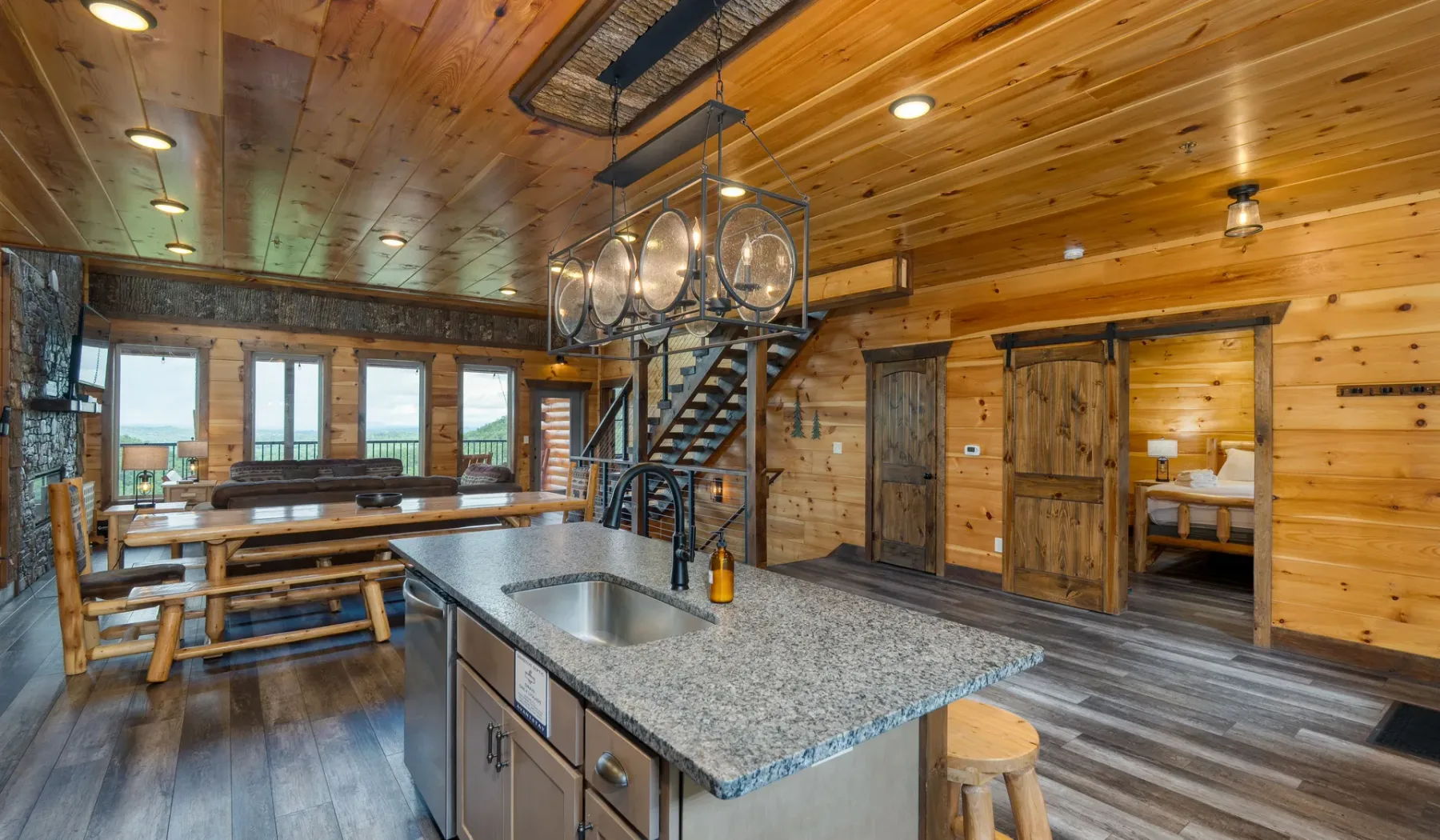 Cocina y comedor revestidos de madera, con una isla central y una mesa larga.