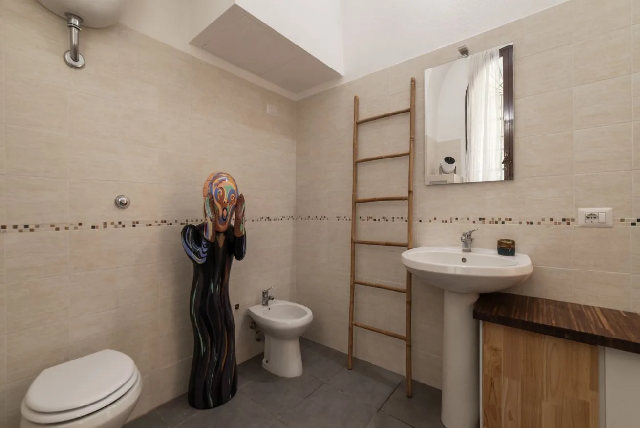 Un baño alicatado con lavabo, espejo y escultura decorativa.