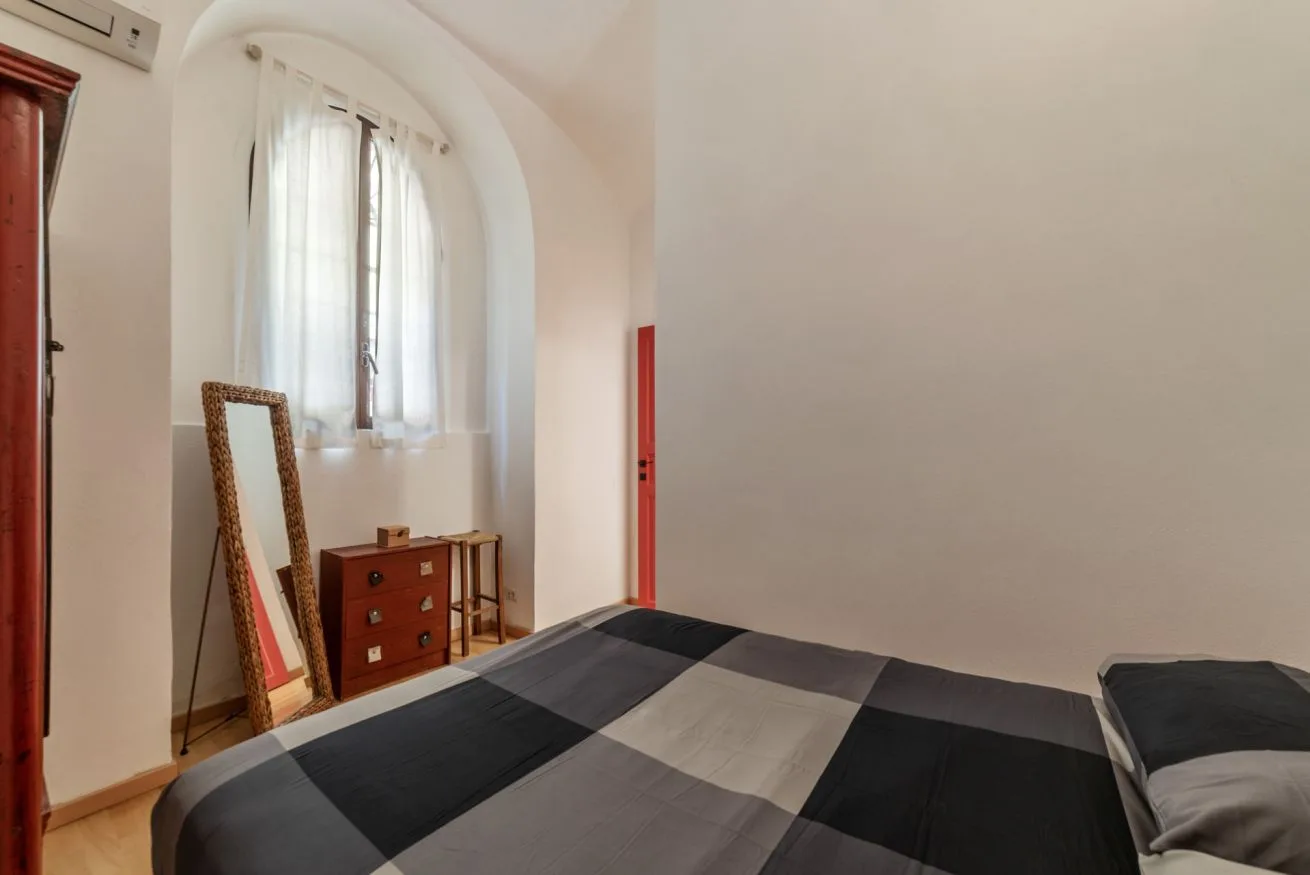 Un dormitorio con una cama, una ventana con cortinas y una cómoda pequeña.