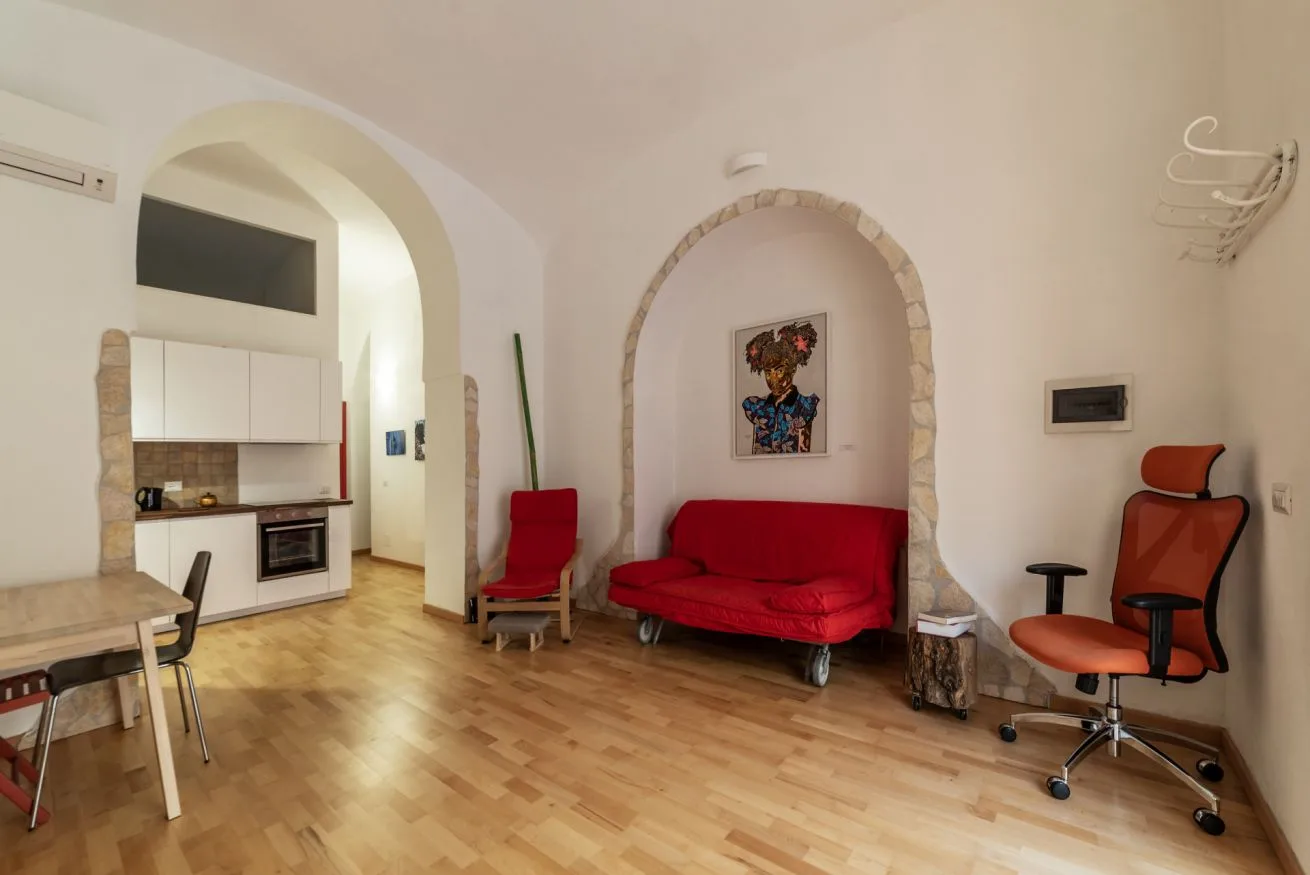Una sala de estar con un sofá rojo y un nicho arqueado.