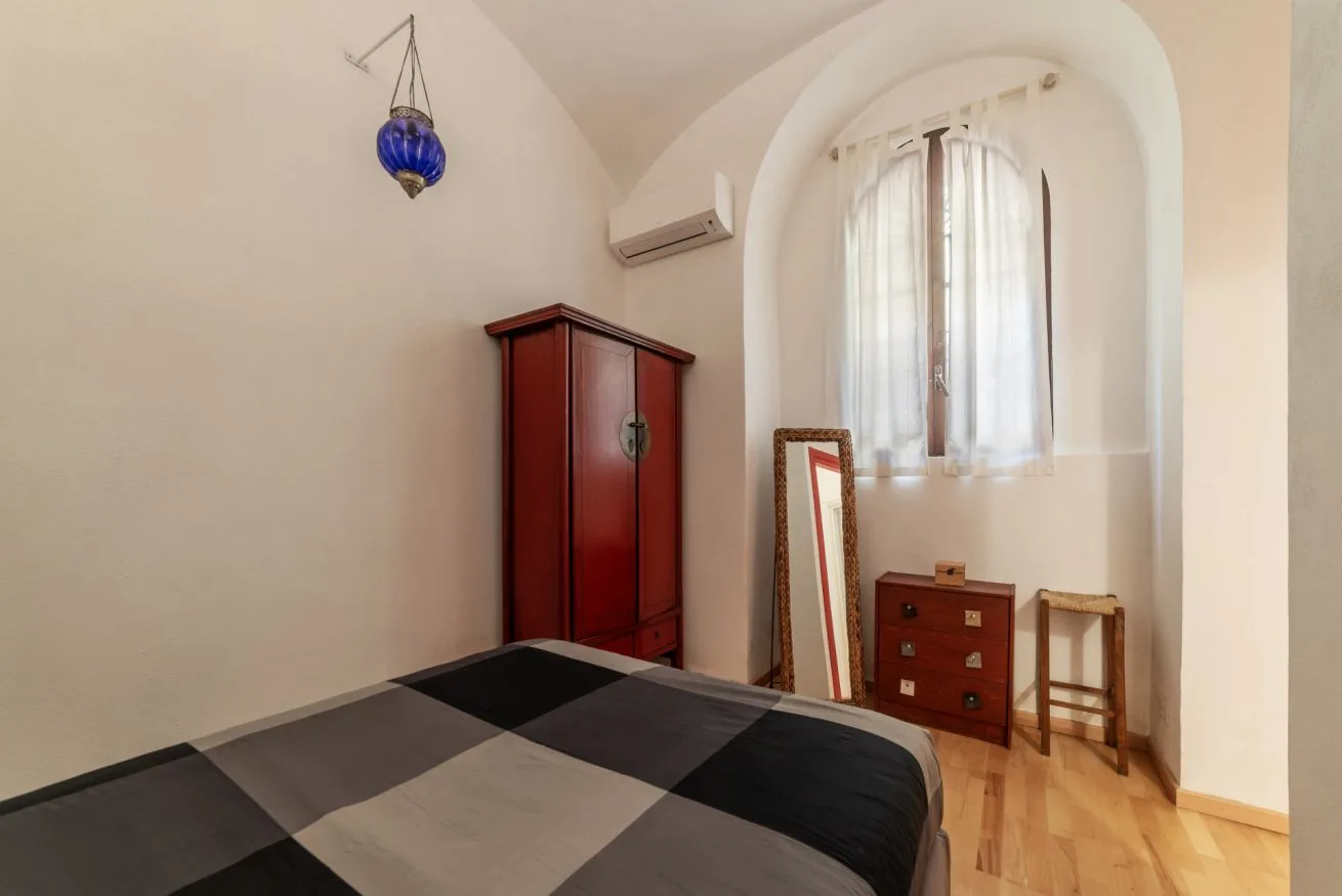 Un dormitorio con una cama, un armario de madera y una ventana con cortinas.