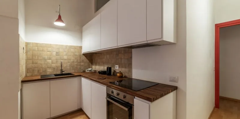 Una cocina compacta con encimeras en L, armarios superiores y un horno integrado.
