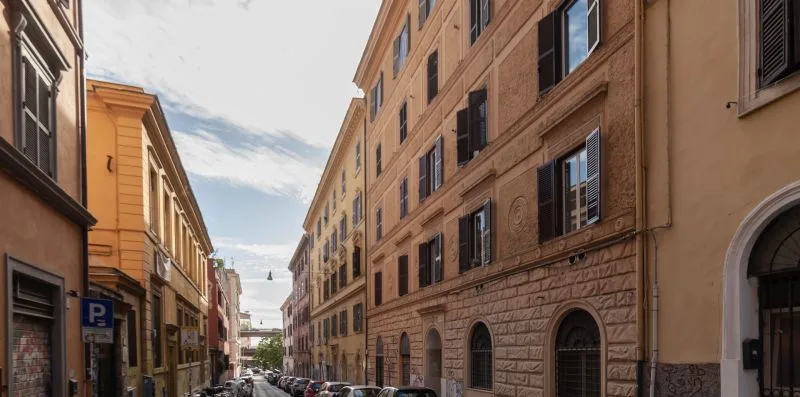 Una calle urbana estrecha flanqueada por edificios altos y coches estacionados.