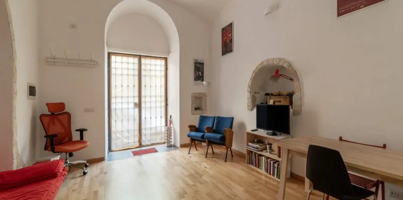 A bright room with a glazed door, blue seating, and a desk.
