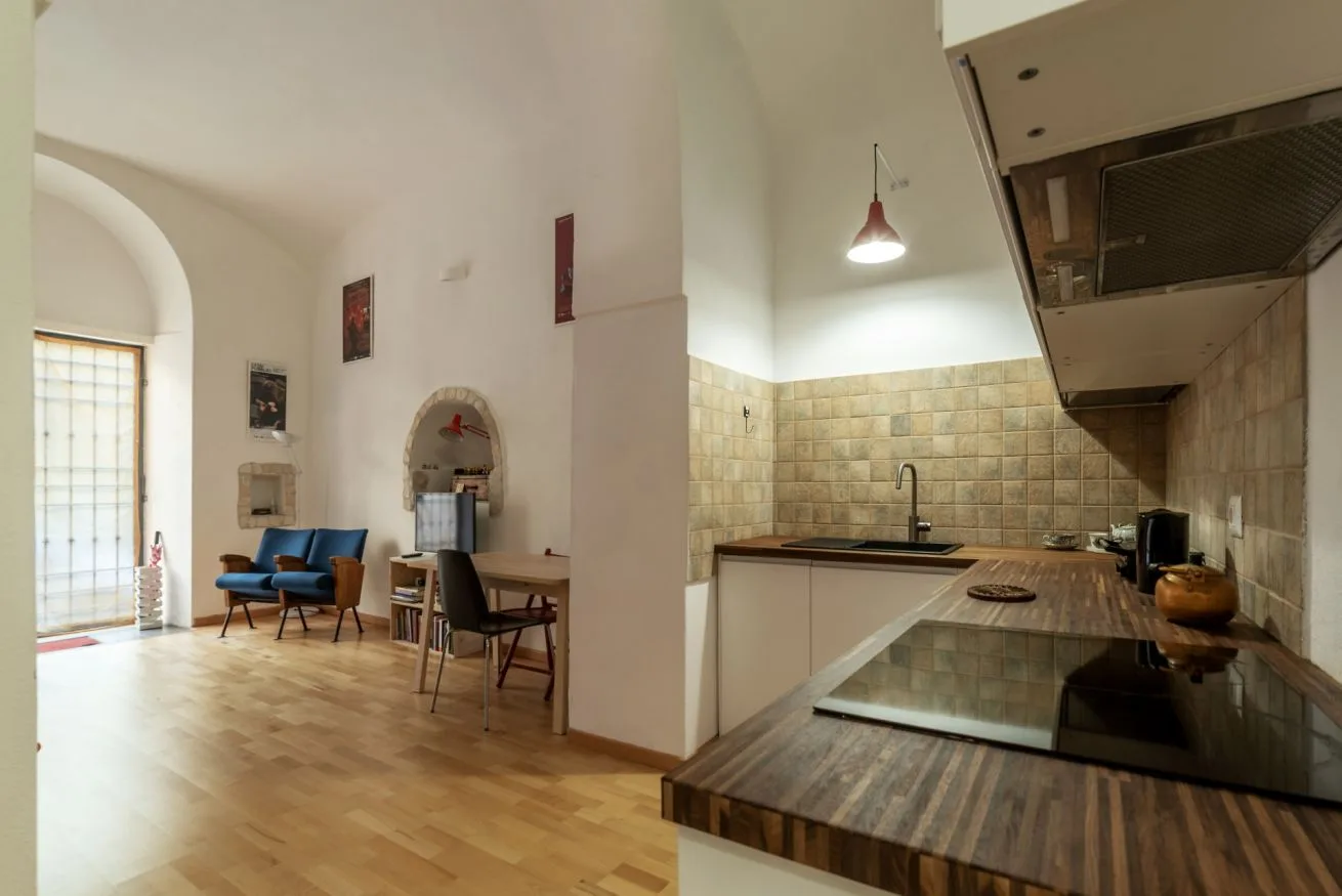 Una cocina abierta con comedor y un pequeño rincón de estar junto a una ventana arqueada.