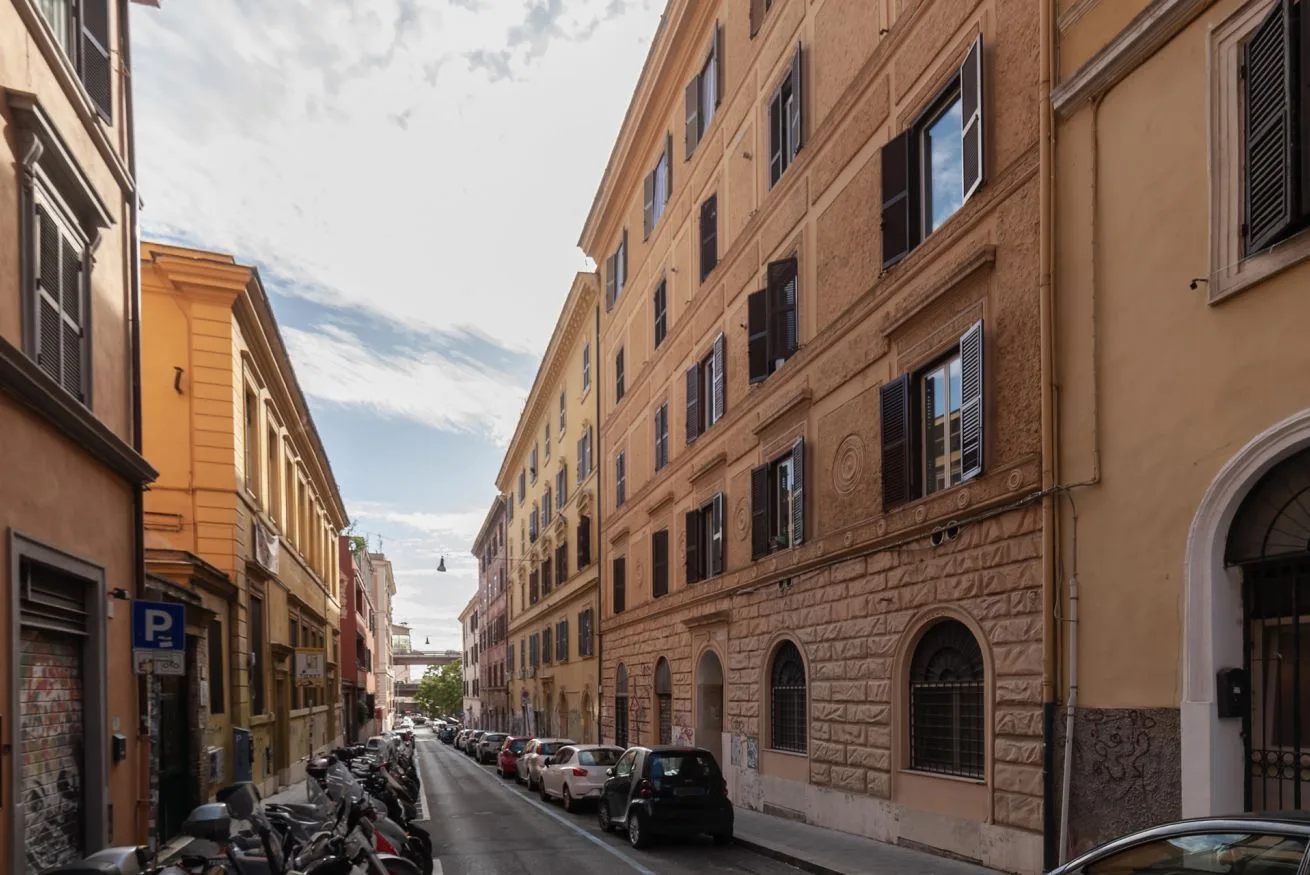 Una calle estrecha de la ciudad bordeada de edificios altos y coches estacionados.