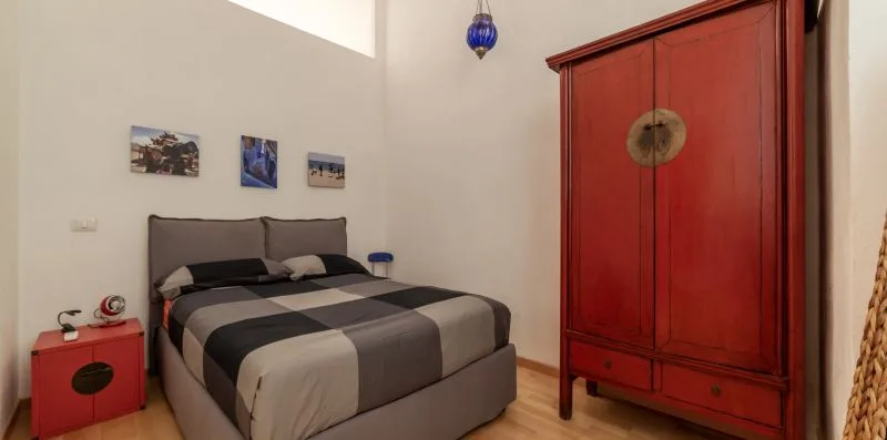 Un dormitorio con una cama y un gran armario rojo.