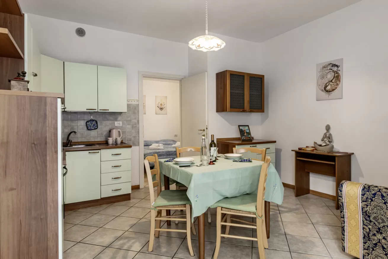 A dining area with a table set beside a compact kitchen.