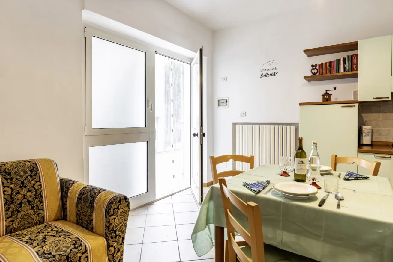 A dining area with a table set beside a patterned sofa and a bright glass door.
