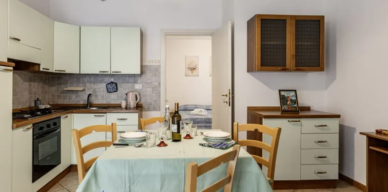 A dining table is set in a kitchen with cabinets, a stove, and a countertop.